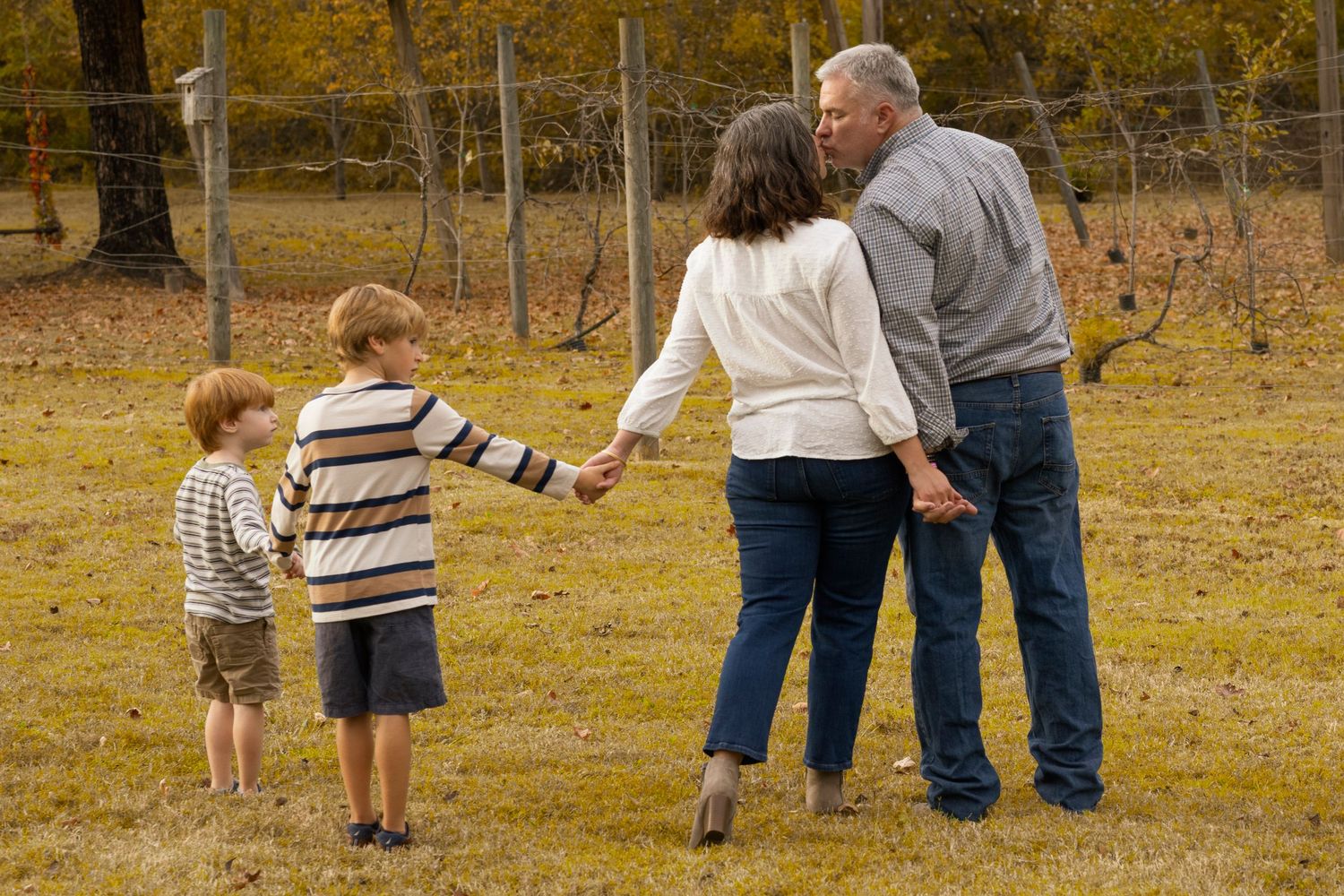 People walking together through a field with autumn trees in the background.