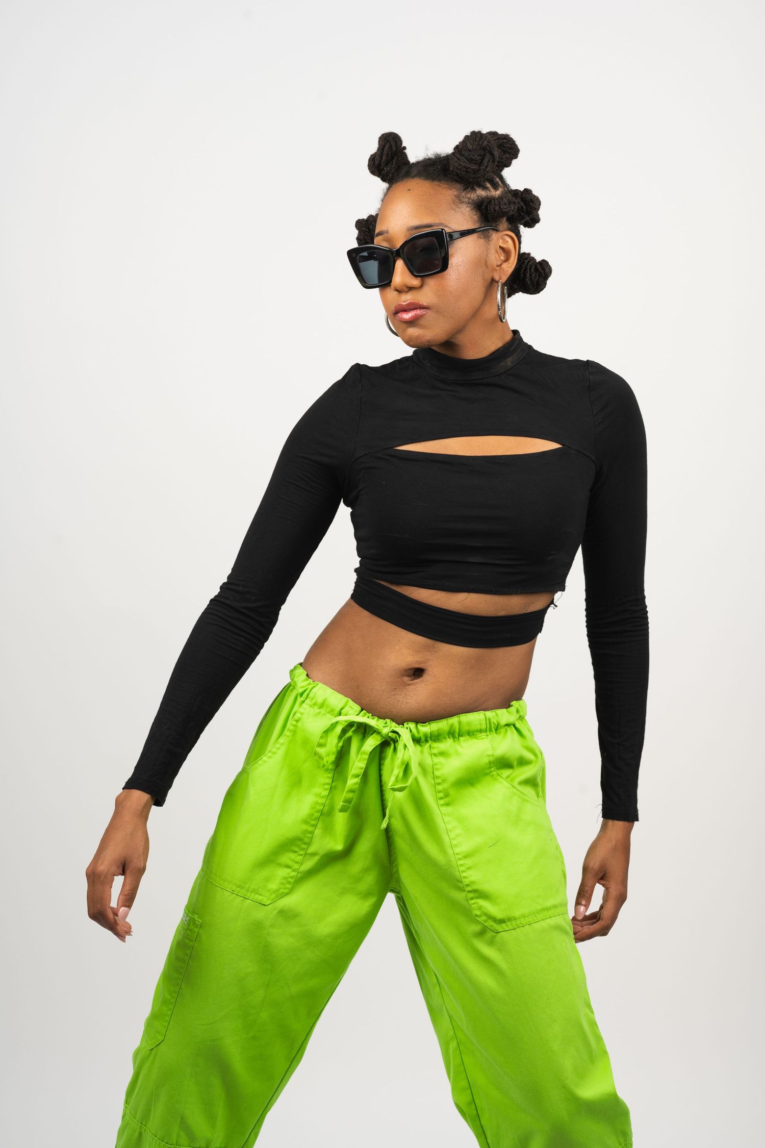 Dancer in black crop top and neon green pants striking urban dance poses.