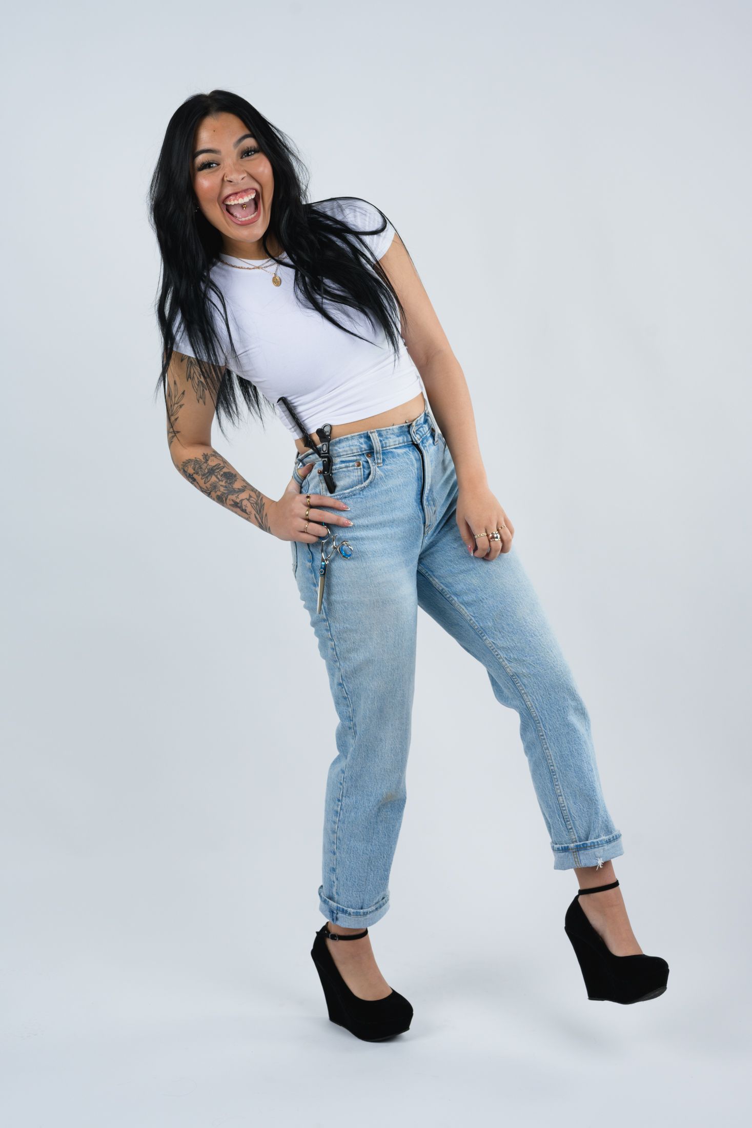 Energetic fashion pose in cropped white top and vintage jeans against white background.