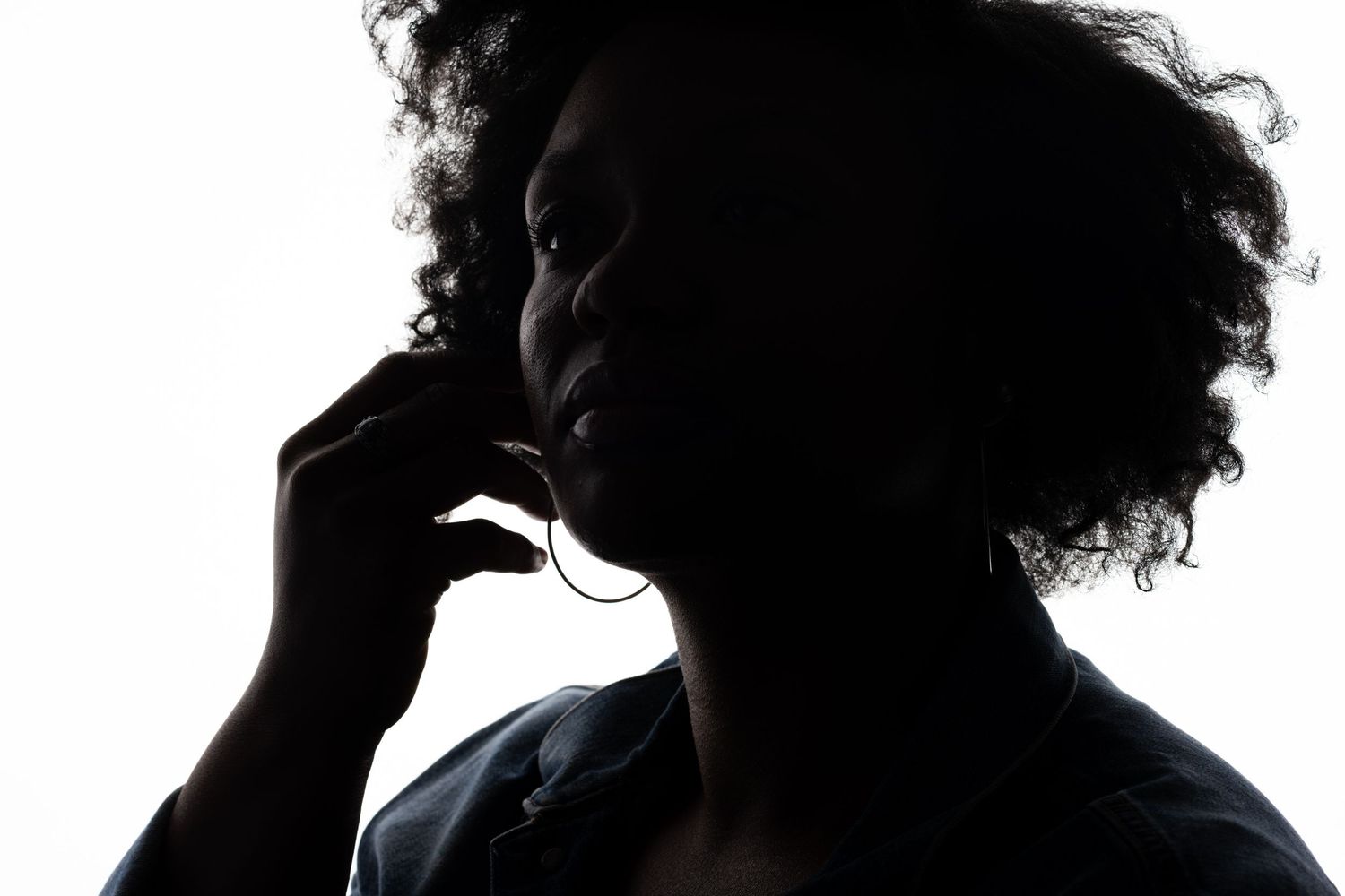 Silhouette profile portrait against white background showing natural curly hair.