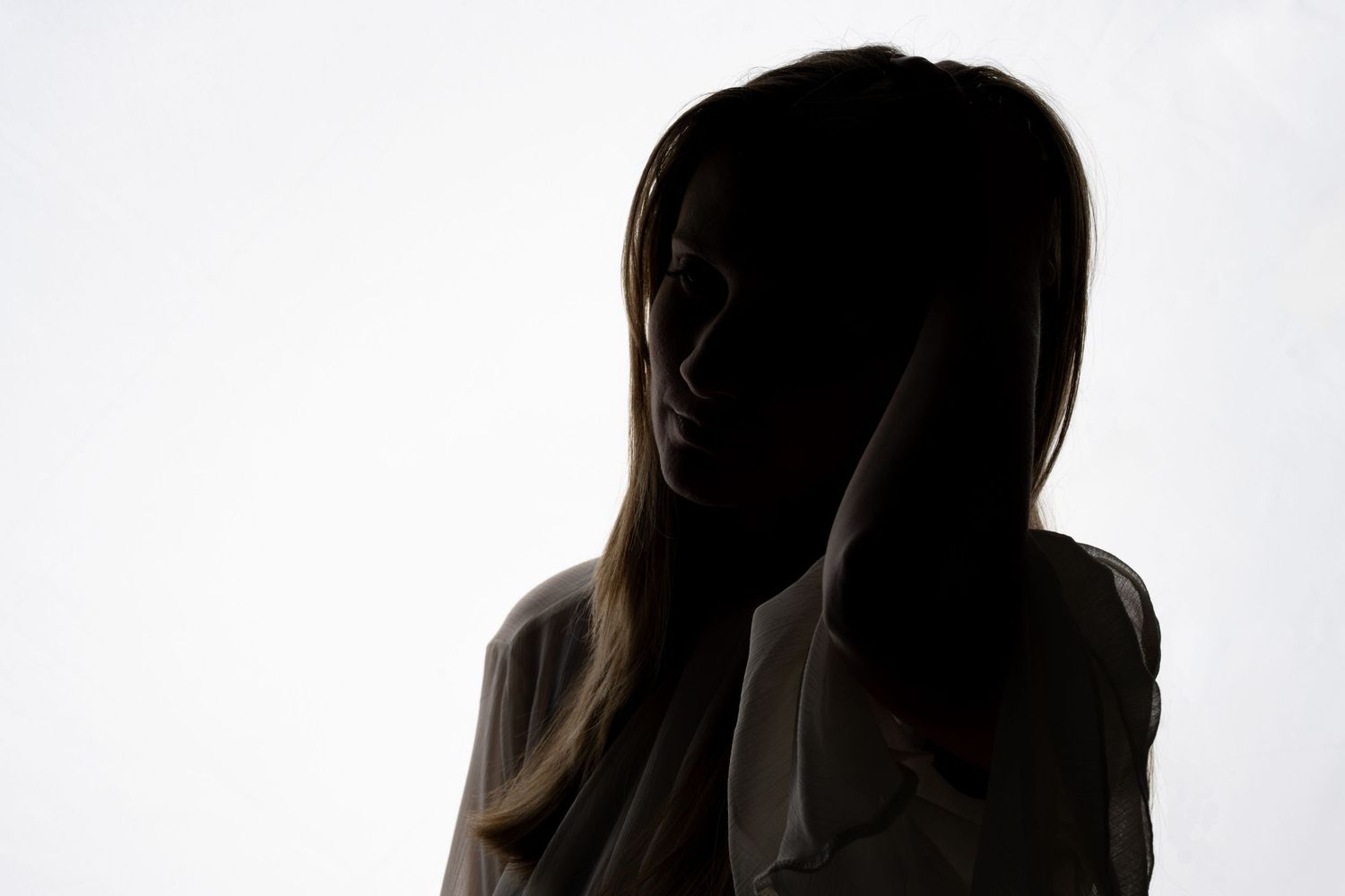 Silhouette of figure in dramatic pose against white backdrop.