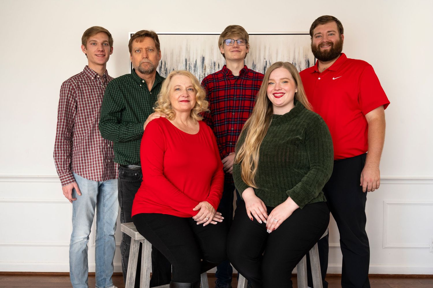 Extended family members posed together in coordinated red and dark clothing for formal portrait.