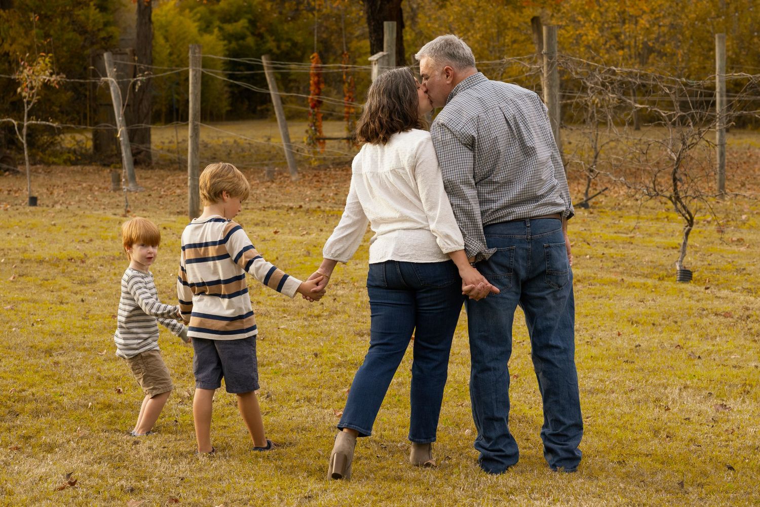 Family group walking together in an autumn field during golden hour.