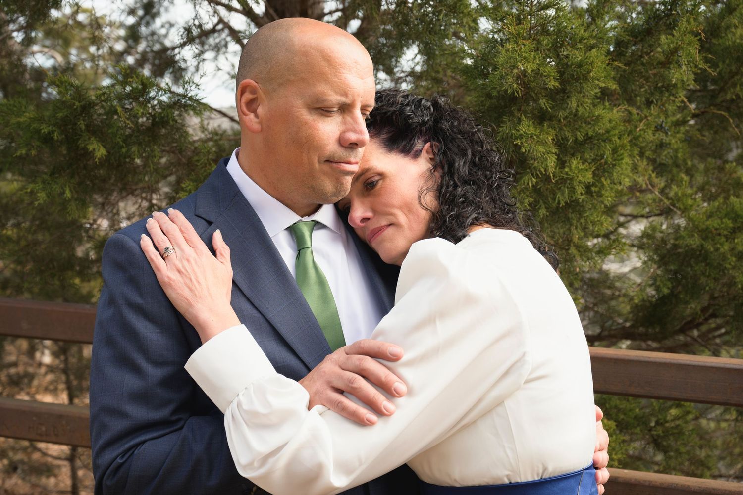 Intimate wedding portrait moments captured outdoors with couples embracing against natural backdrop.