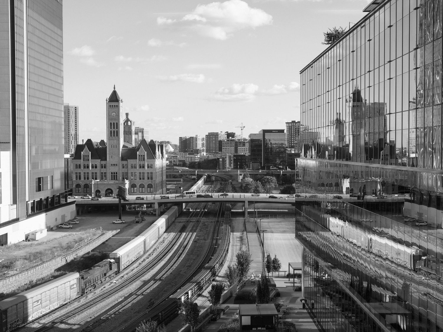 Panoramic cityscape view of skyscrapers and train tracks from an office building window.