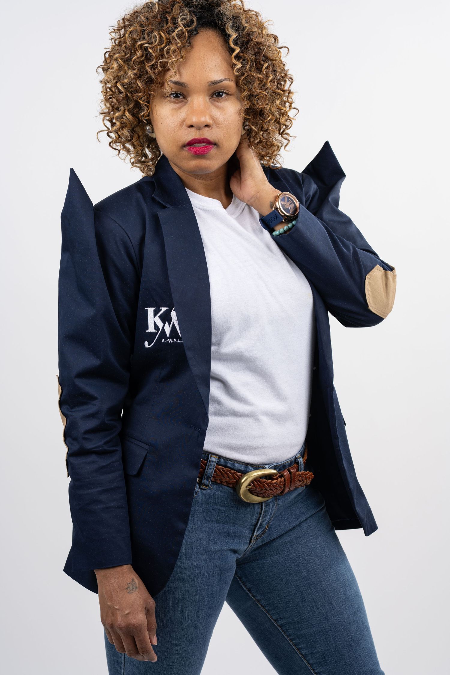 Professional portrait of woman in navy blazer and white shirt with natural curly hair.