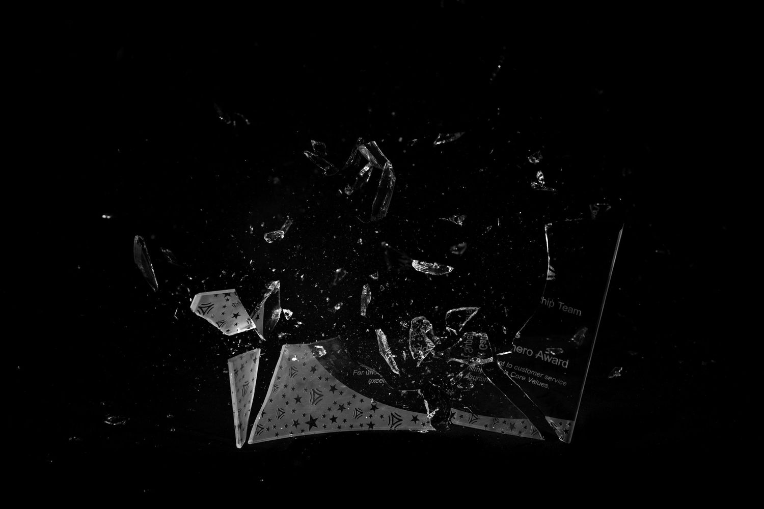 A broken shattered glass or mirror piece reflecting light against a dark black background.