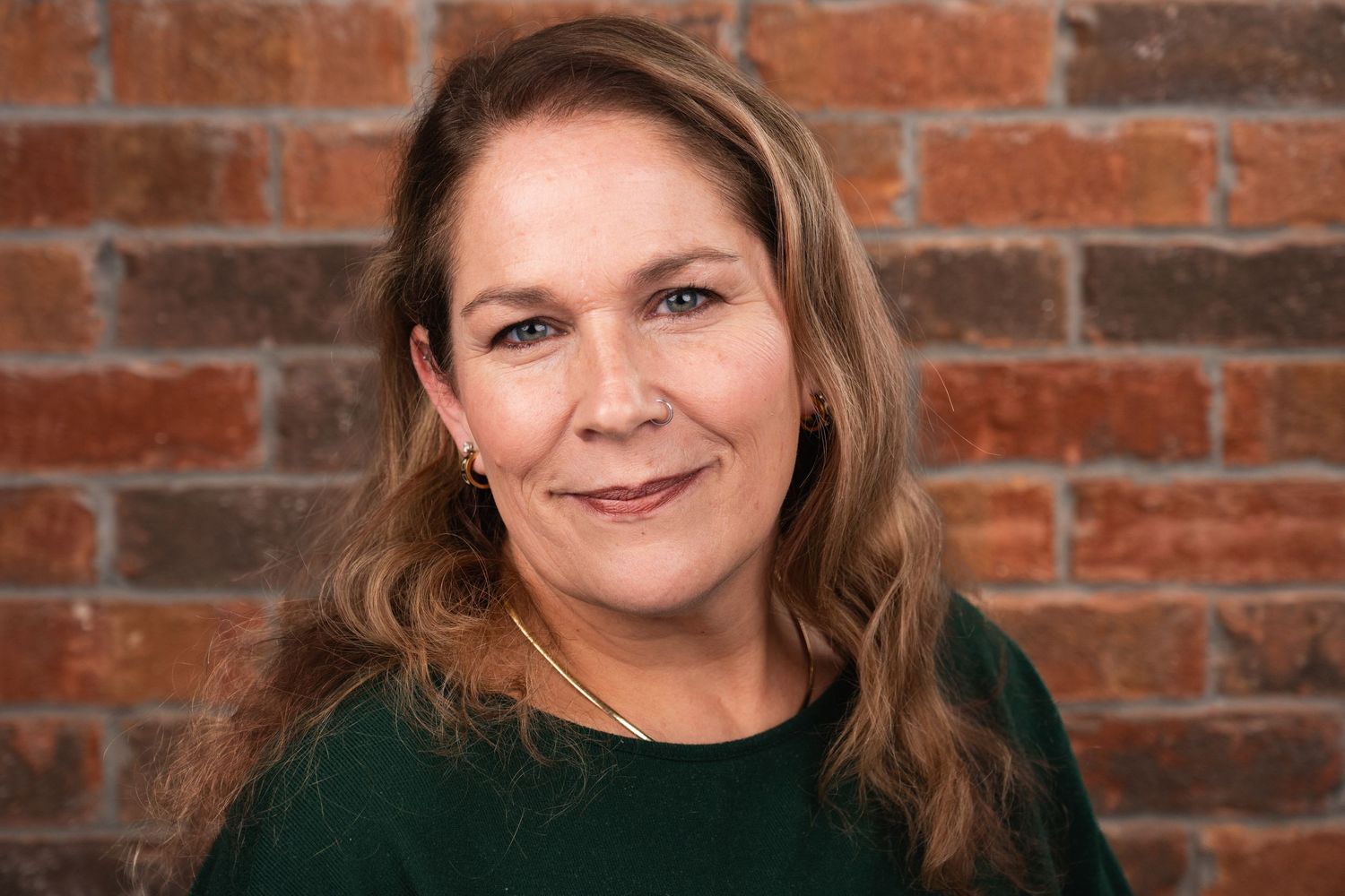 Professional headshot against brick wall background.
