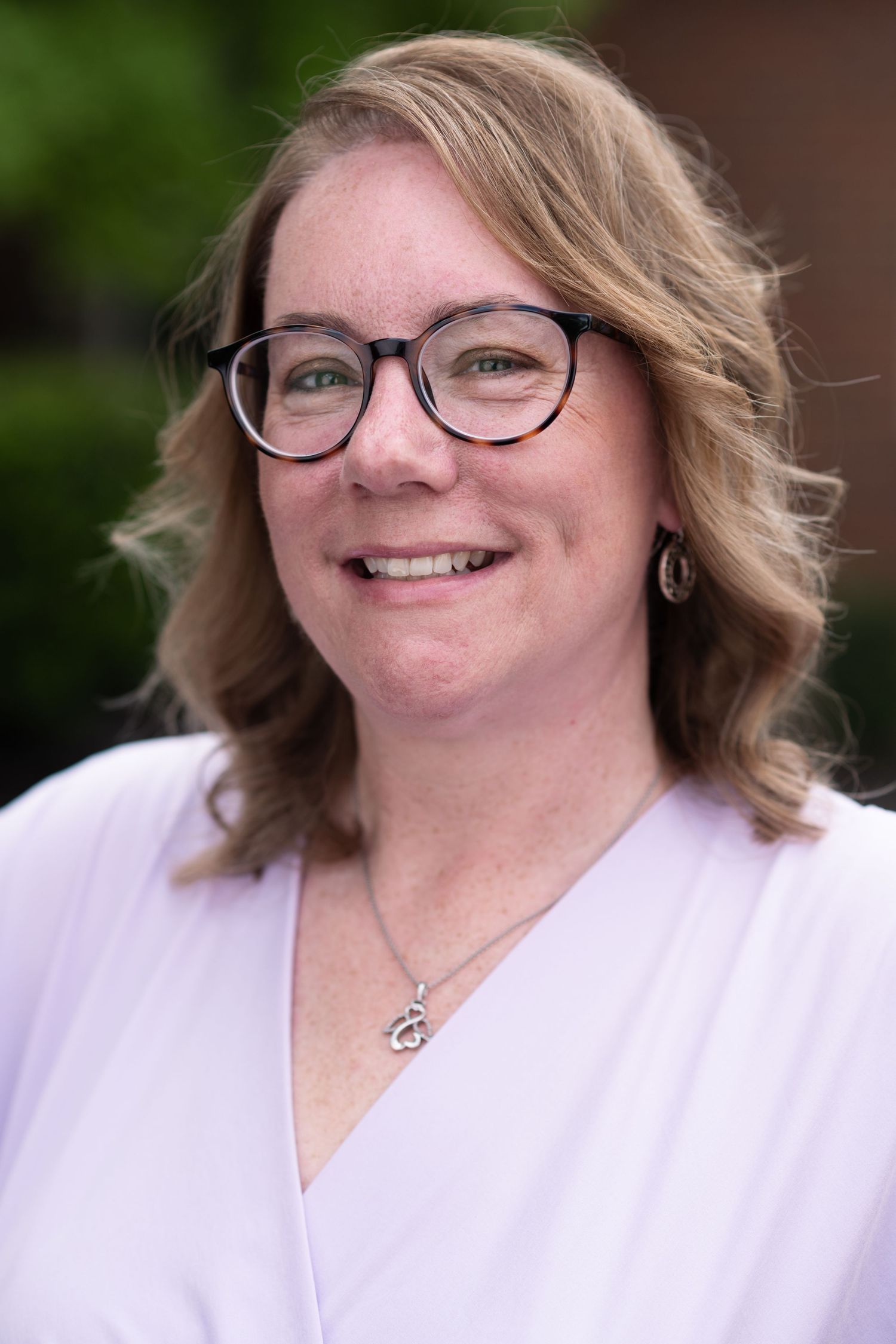 Professional headshots in white attire against outdoor background with natural lighting.