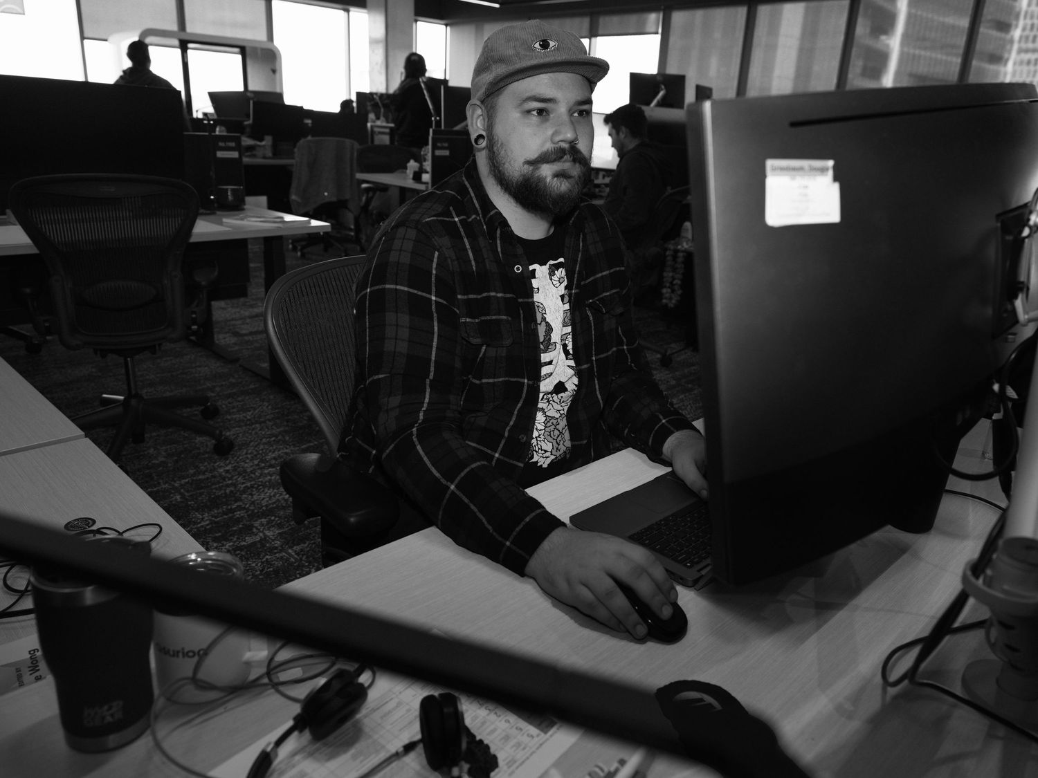 People working at long tables in an open office environment.