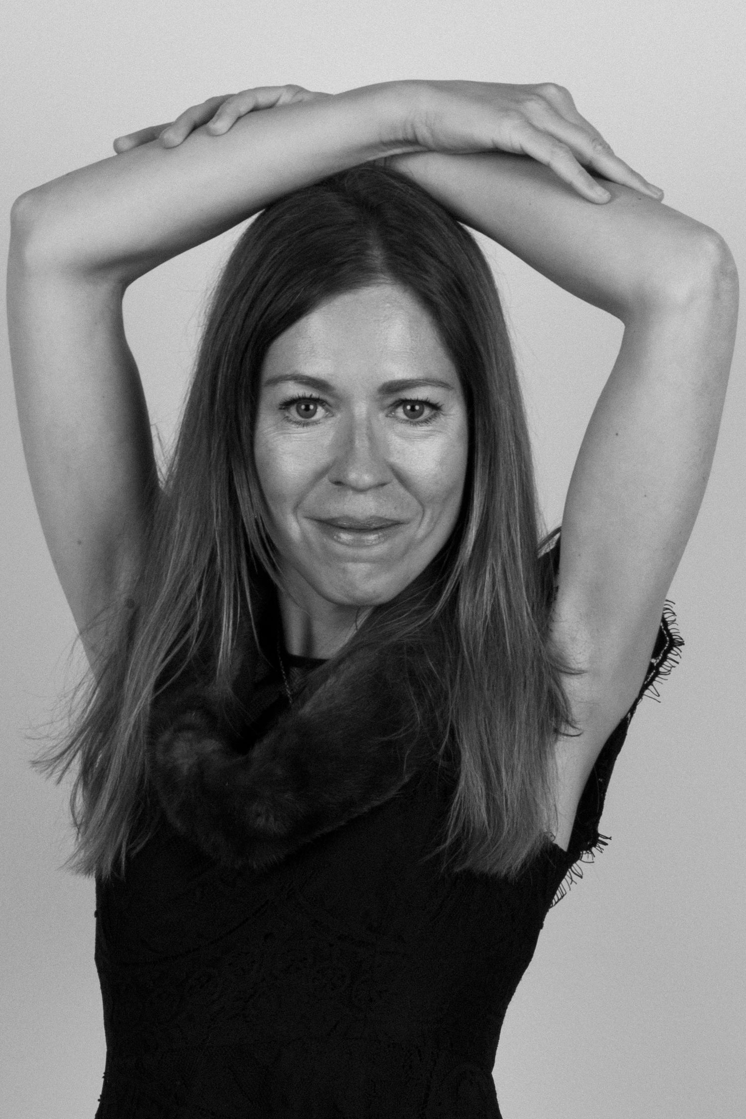 A series of four black and white photos showing someone posing playfully with their hands raised above their head.