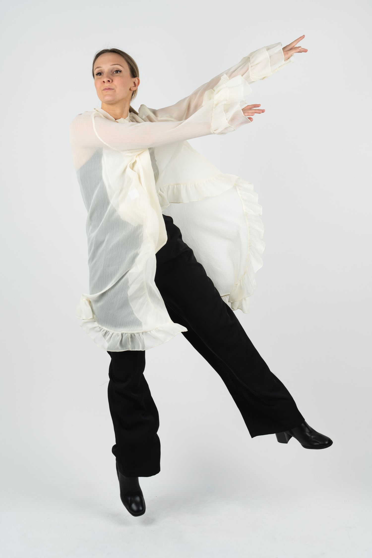Dancer in white shirt and black pants leaping gracefully against white background.
