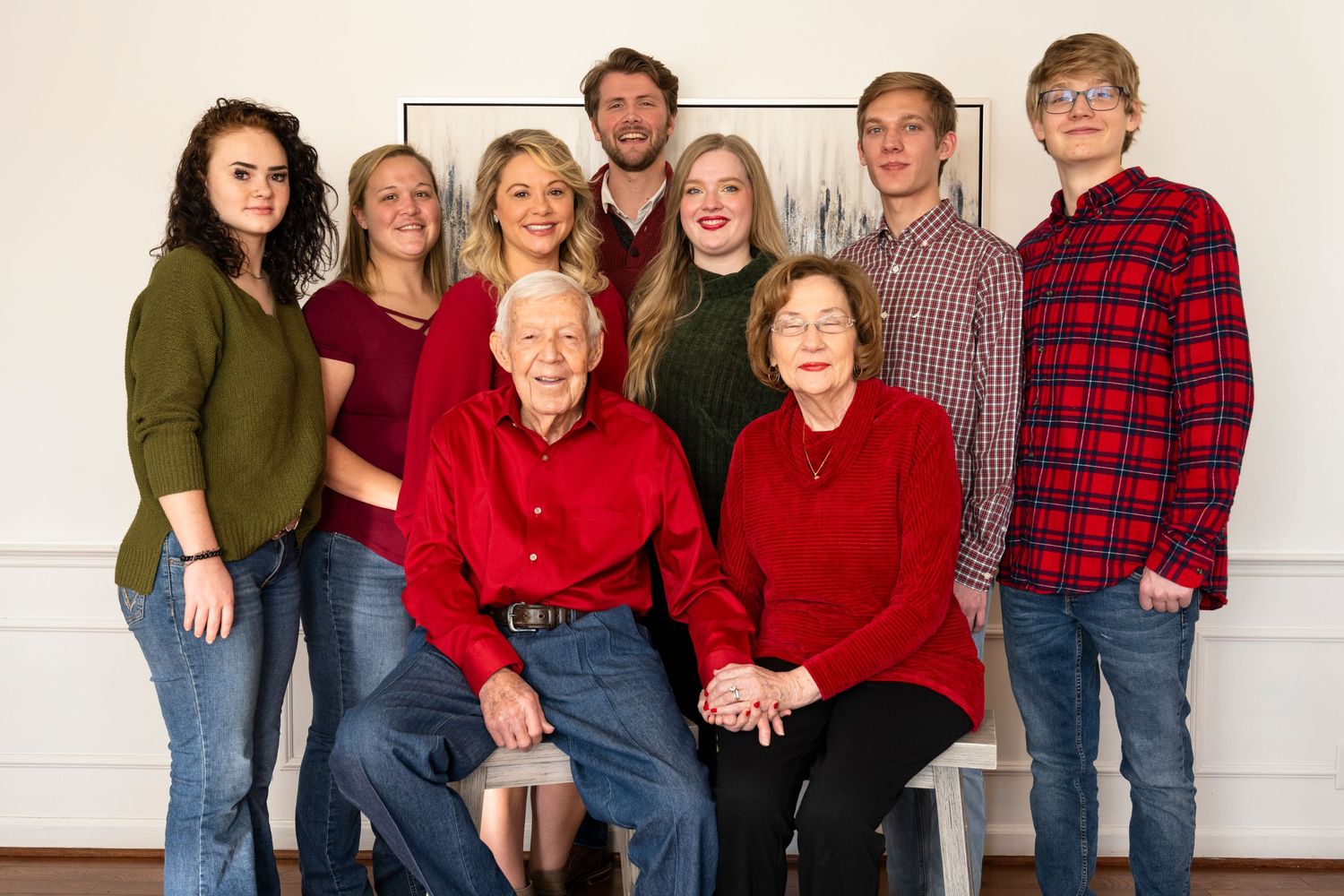 Family portrait with multiple generations wearing matching red and dark colored clothing.