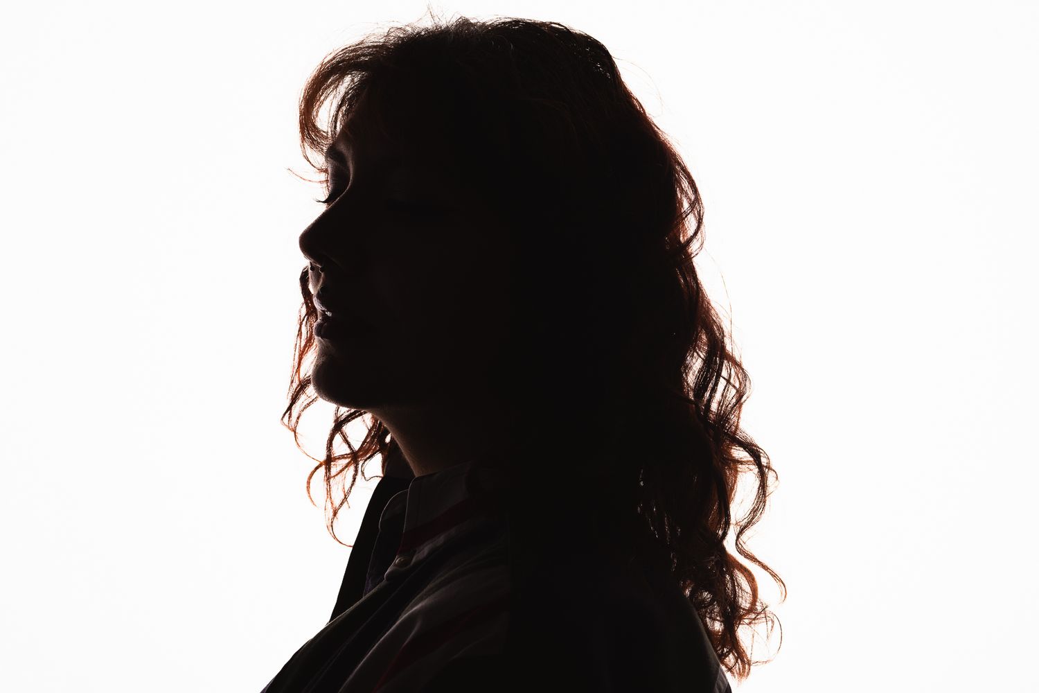 Artistic silhouette portrait against white background showing curly hair detail.