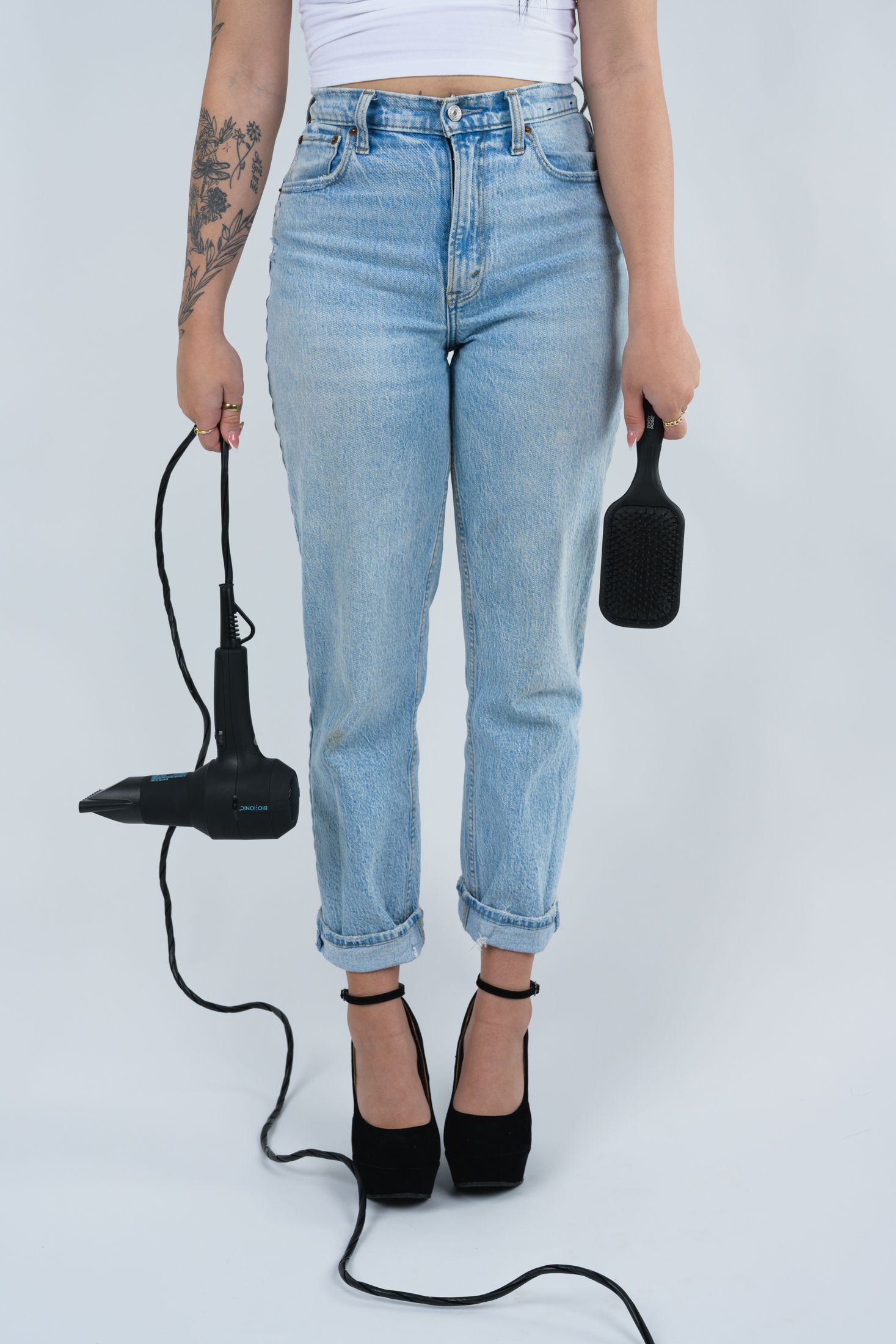 Cropped view of light wash jeans and black shoes with cord detail against white background.