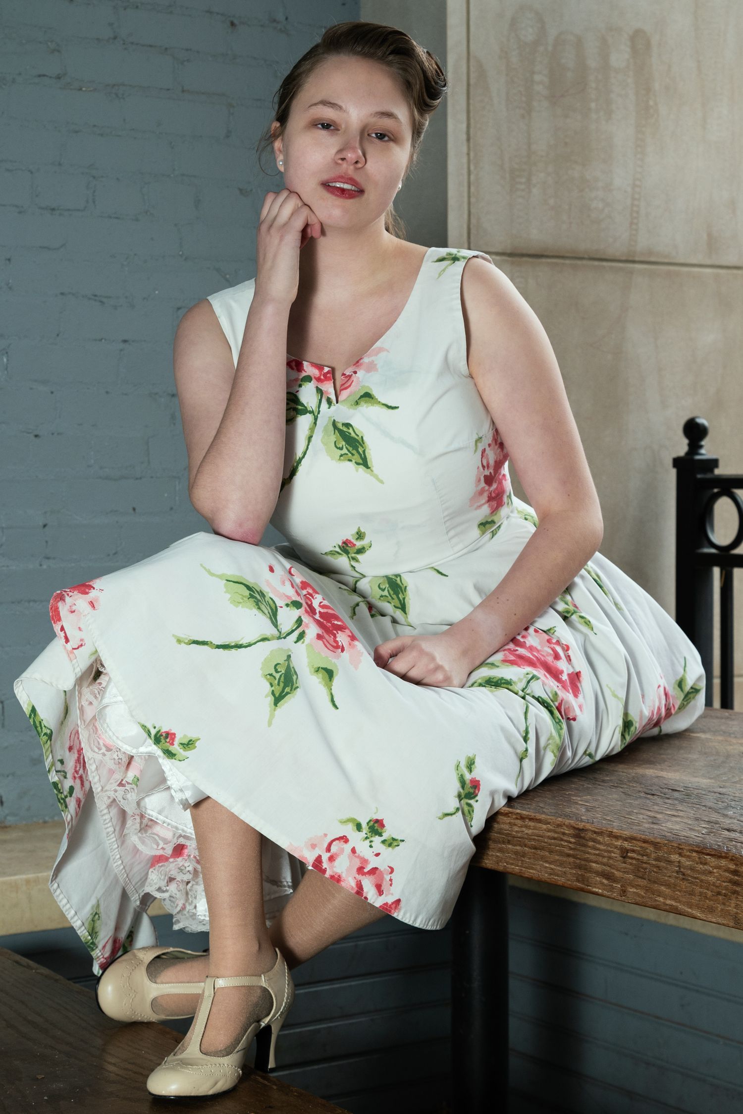Vintage-inspired poses in a floral dress on a wooden bench.
