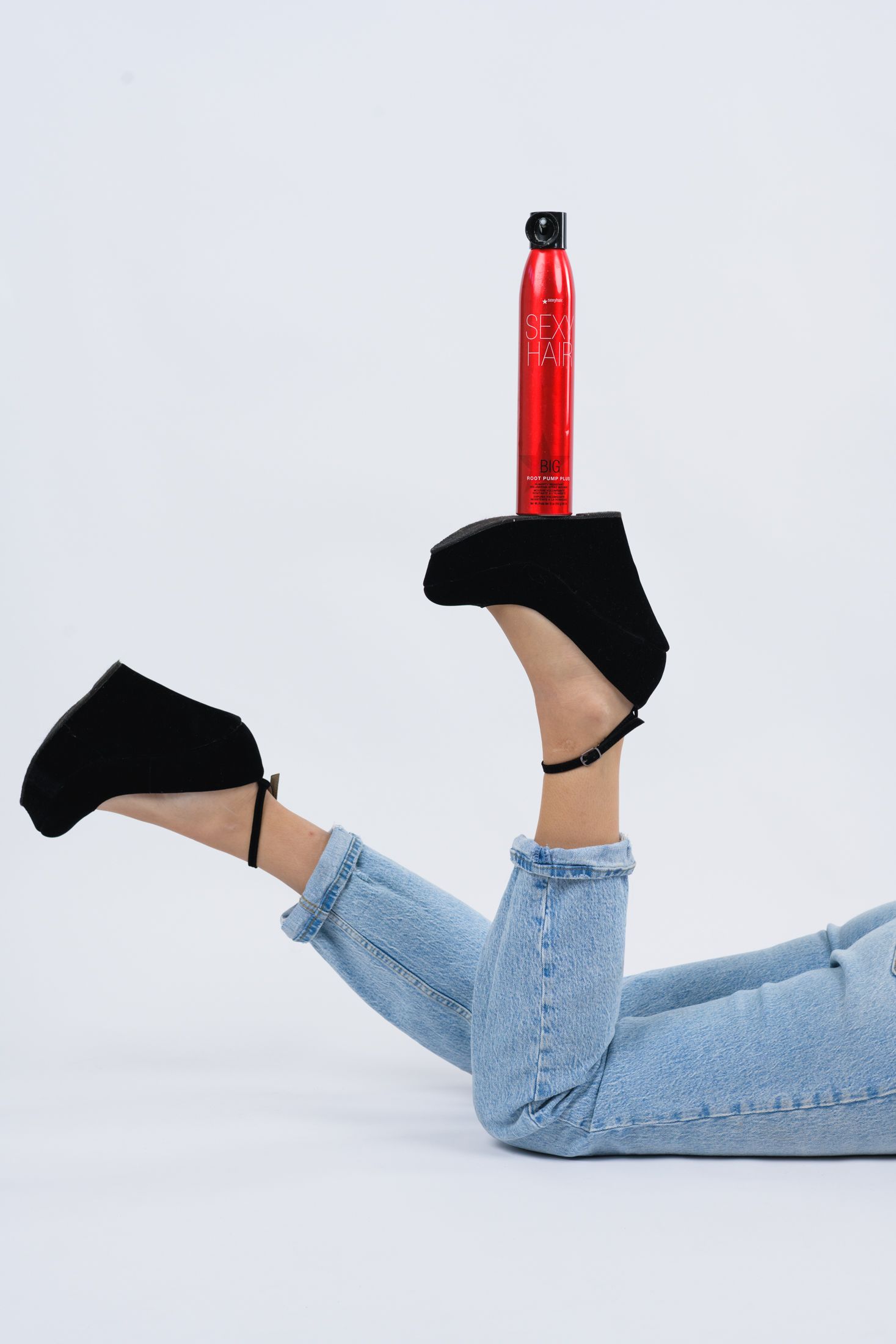 Creative product shot featuring red water bottle balanced on black platform heel.