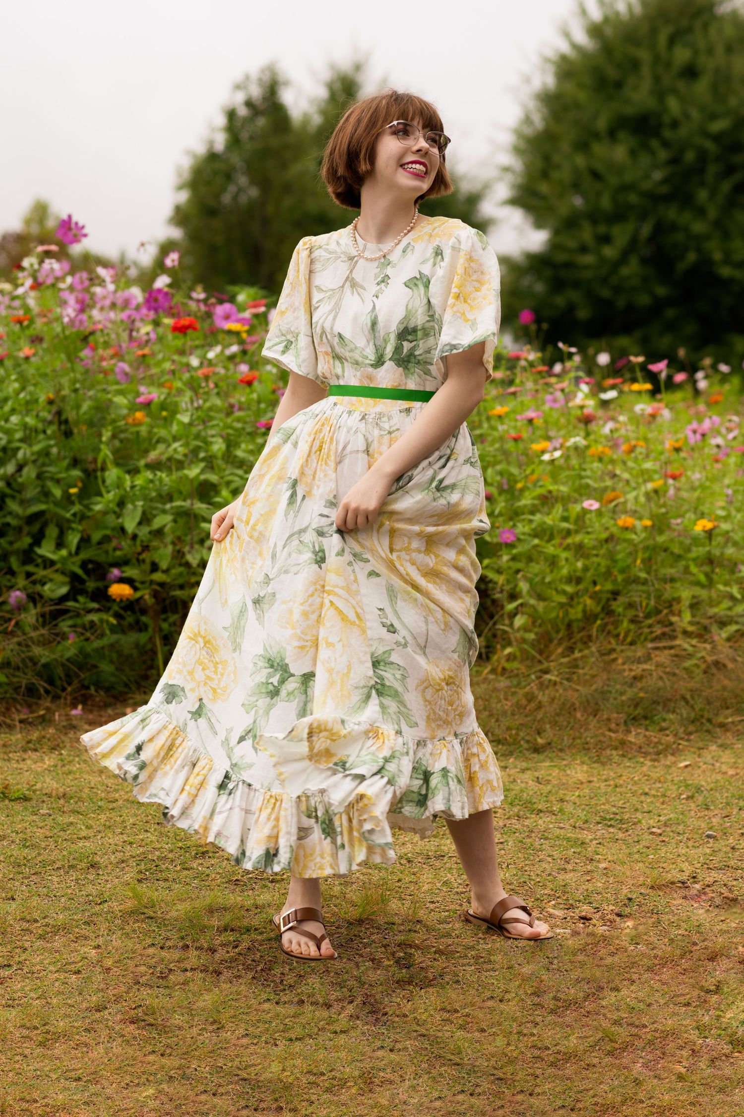 A floral summer dress twirls in a garden filled with colorful wildflowers and green foliage.