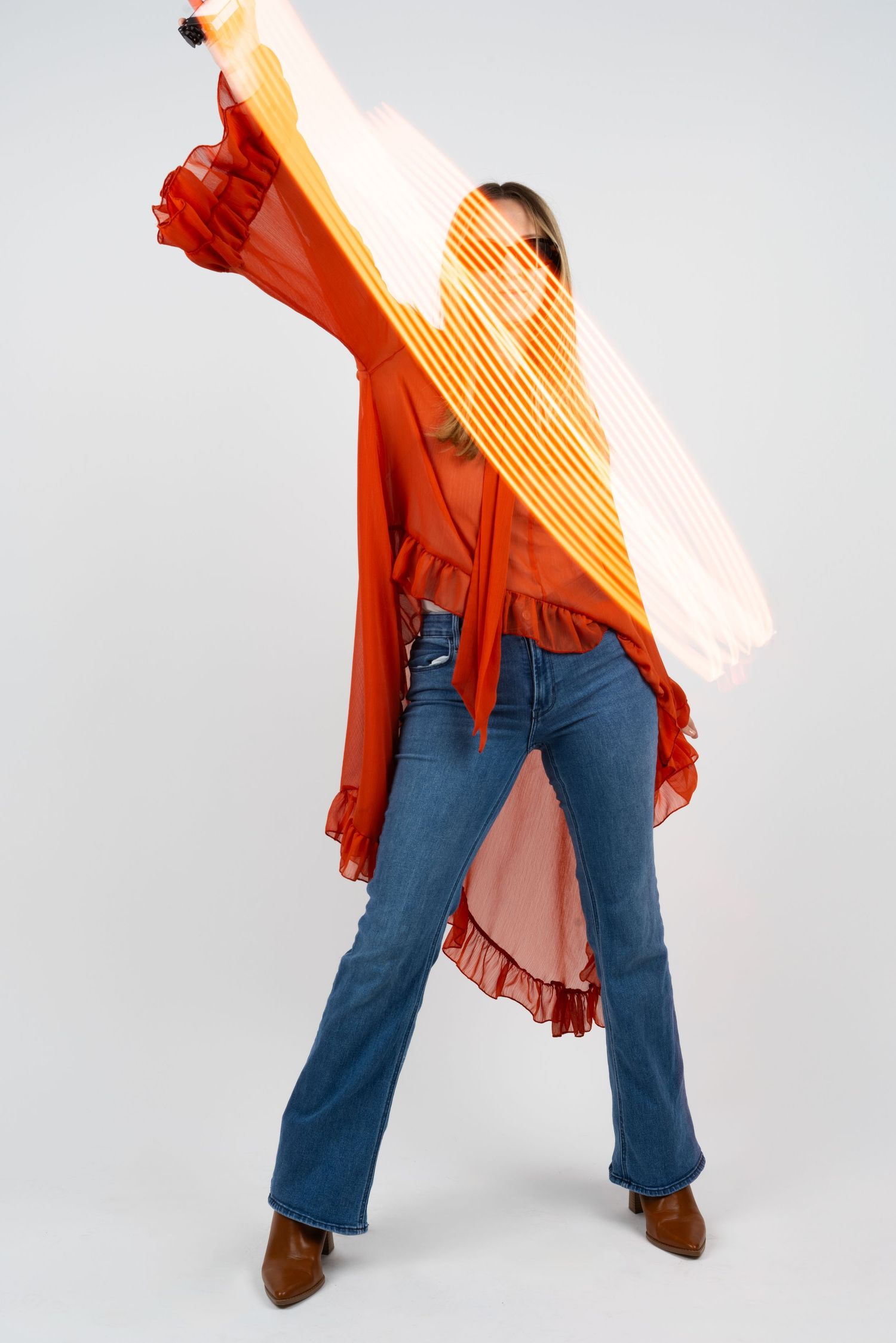 Fashion shot with orange ruffled jacket and jeans creating dynamic movement.