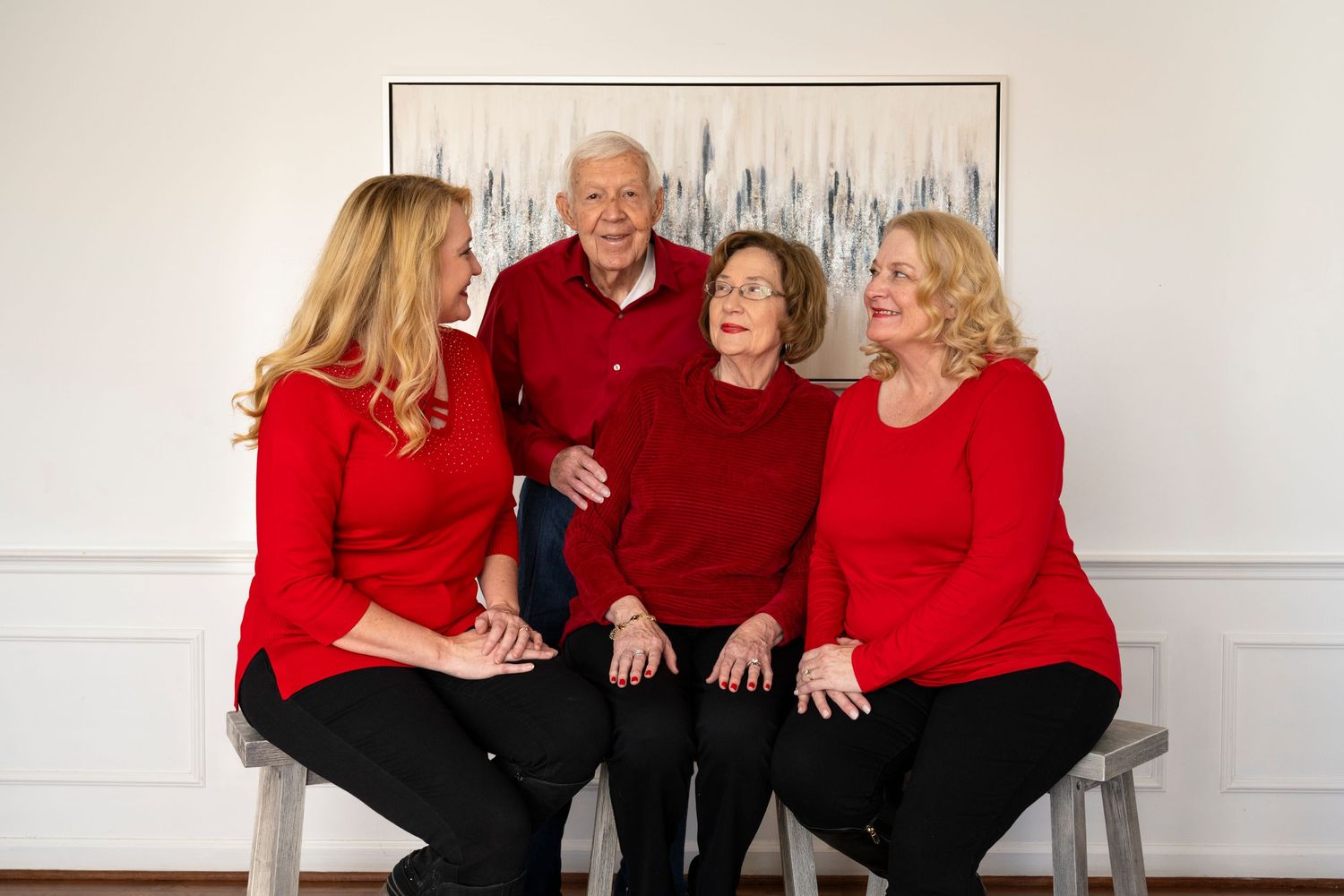 Multi-generational family sitting together wearing red and black clothing for holiday portrait.