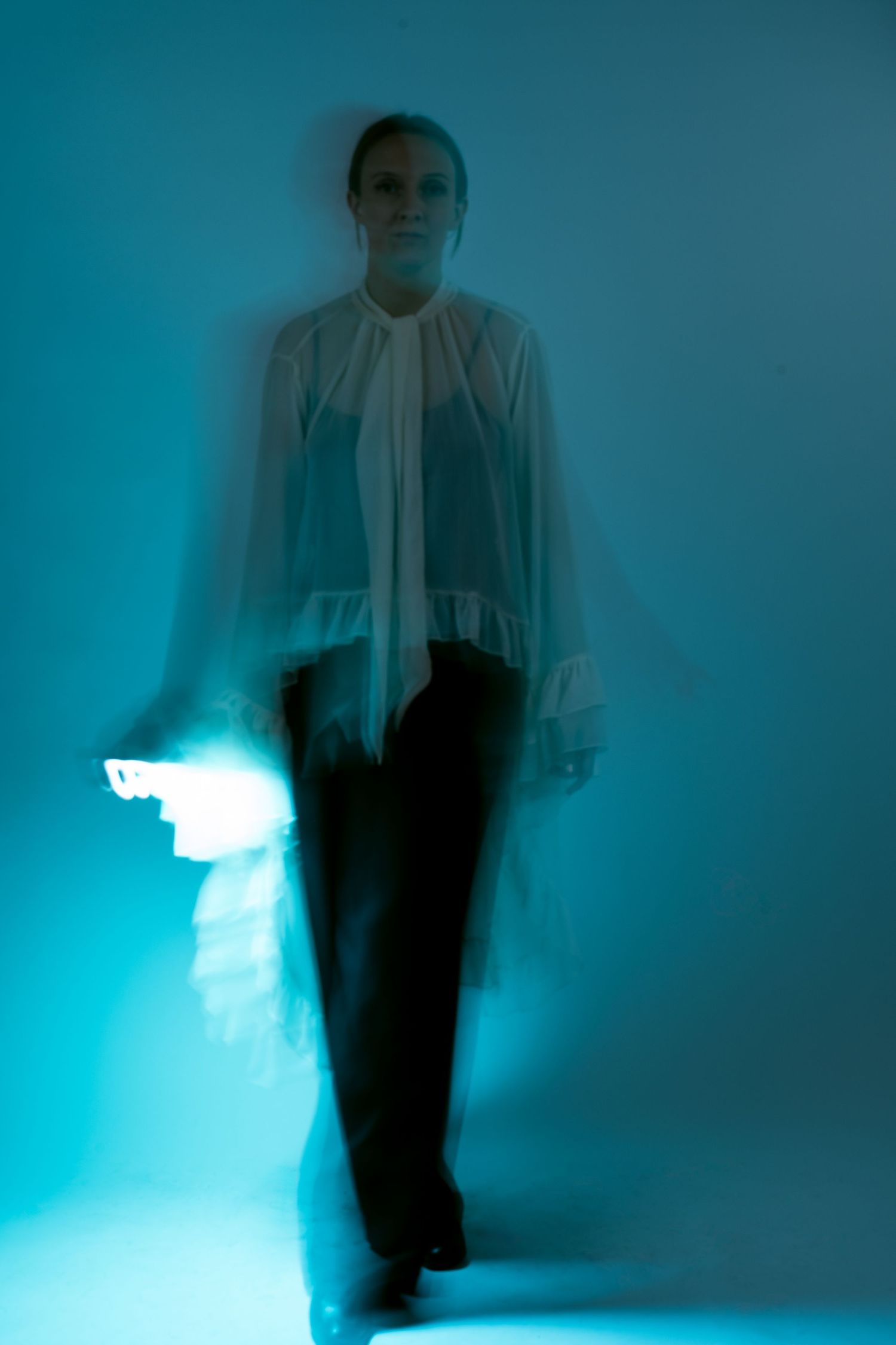 Person in white clothing creates ethereal movement against blue-tinted backdrop.