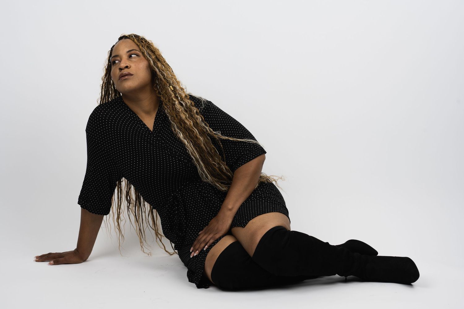 Dancer in black outfit creating fluid movements while lying on white floor.