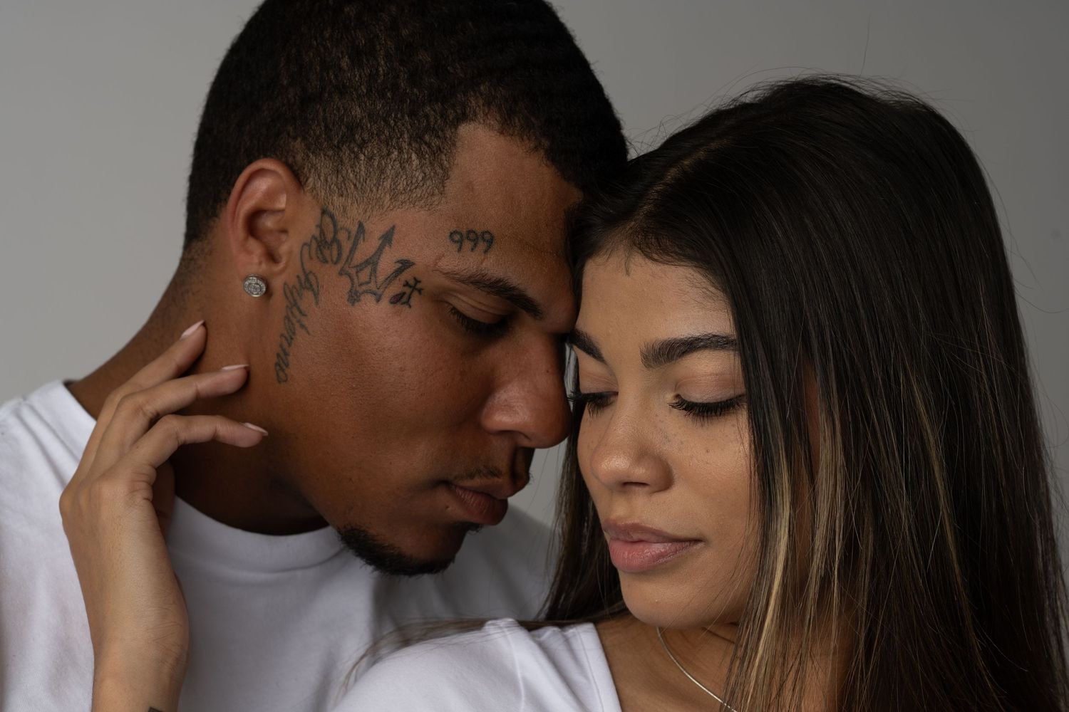 Intimate couple portrait series with dramatic lighting against white background.