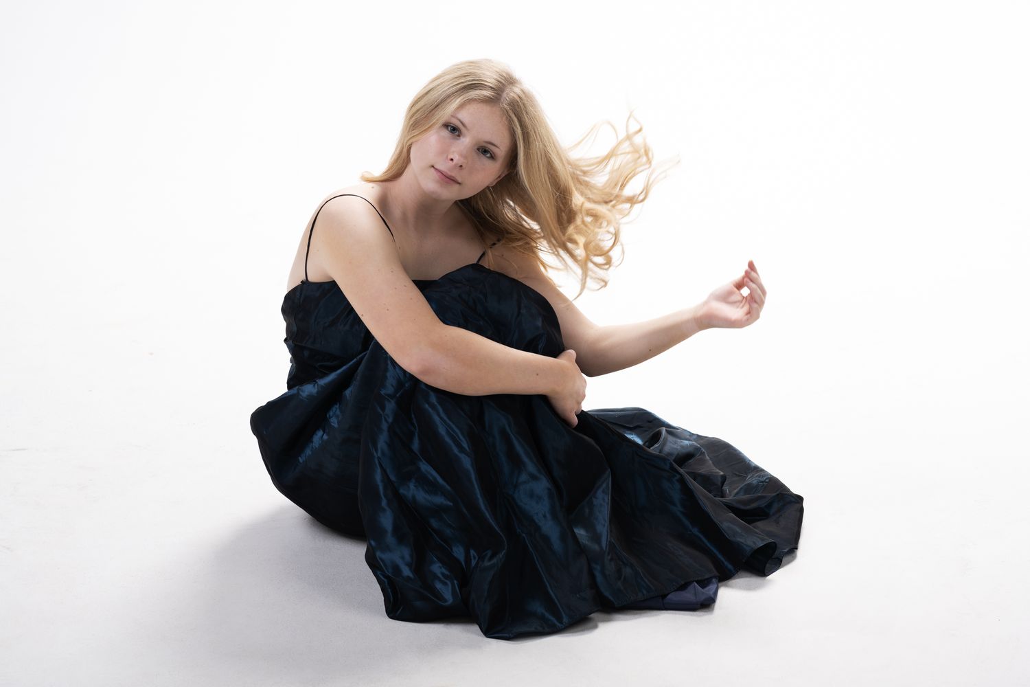 Woman in black dress poses gracefully on white background in artistic photo sequence.