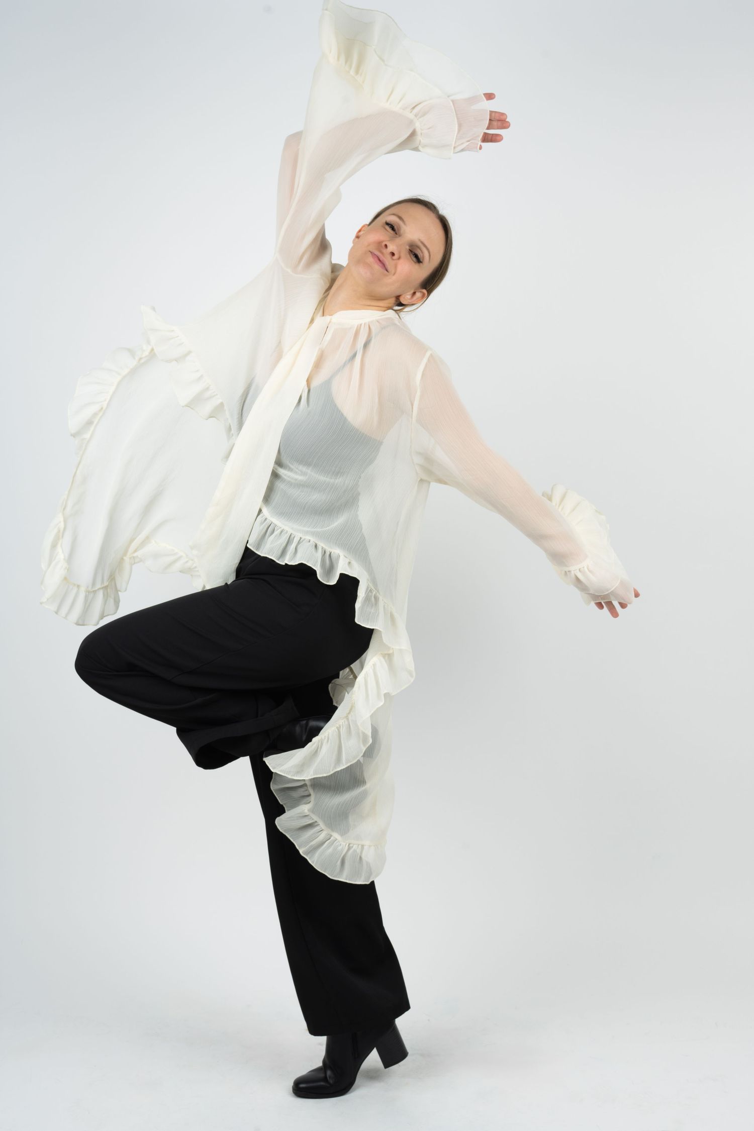 Performer in flowing white top and black pants executing dynamic dance movements.
