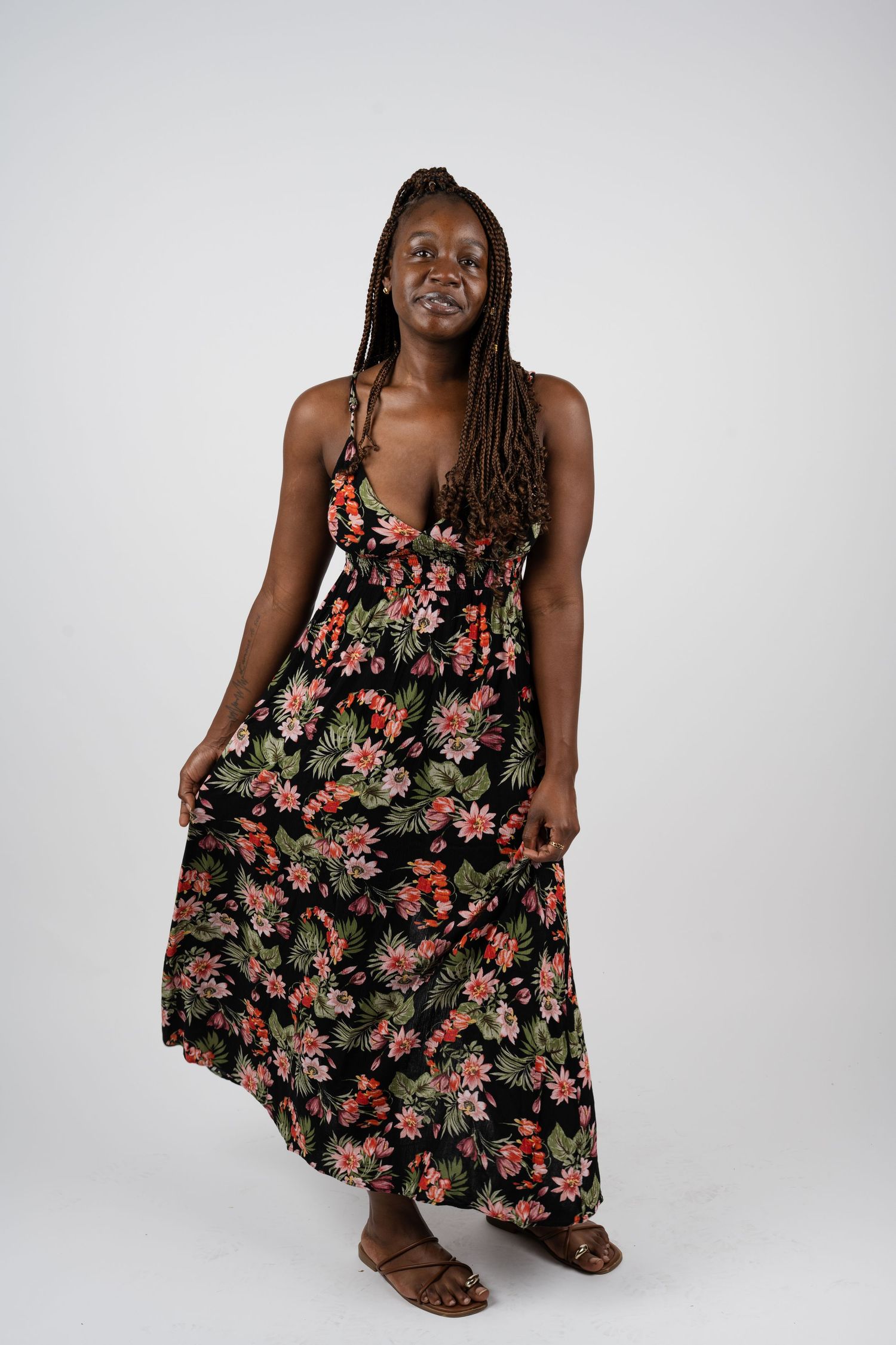 Model wearing floral print maxi dress poses against white studio background.
