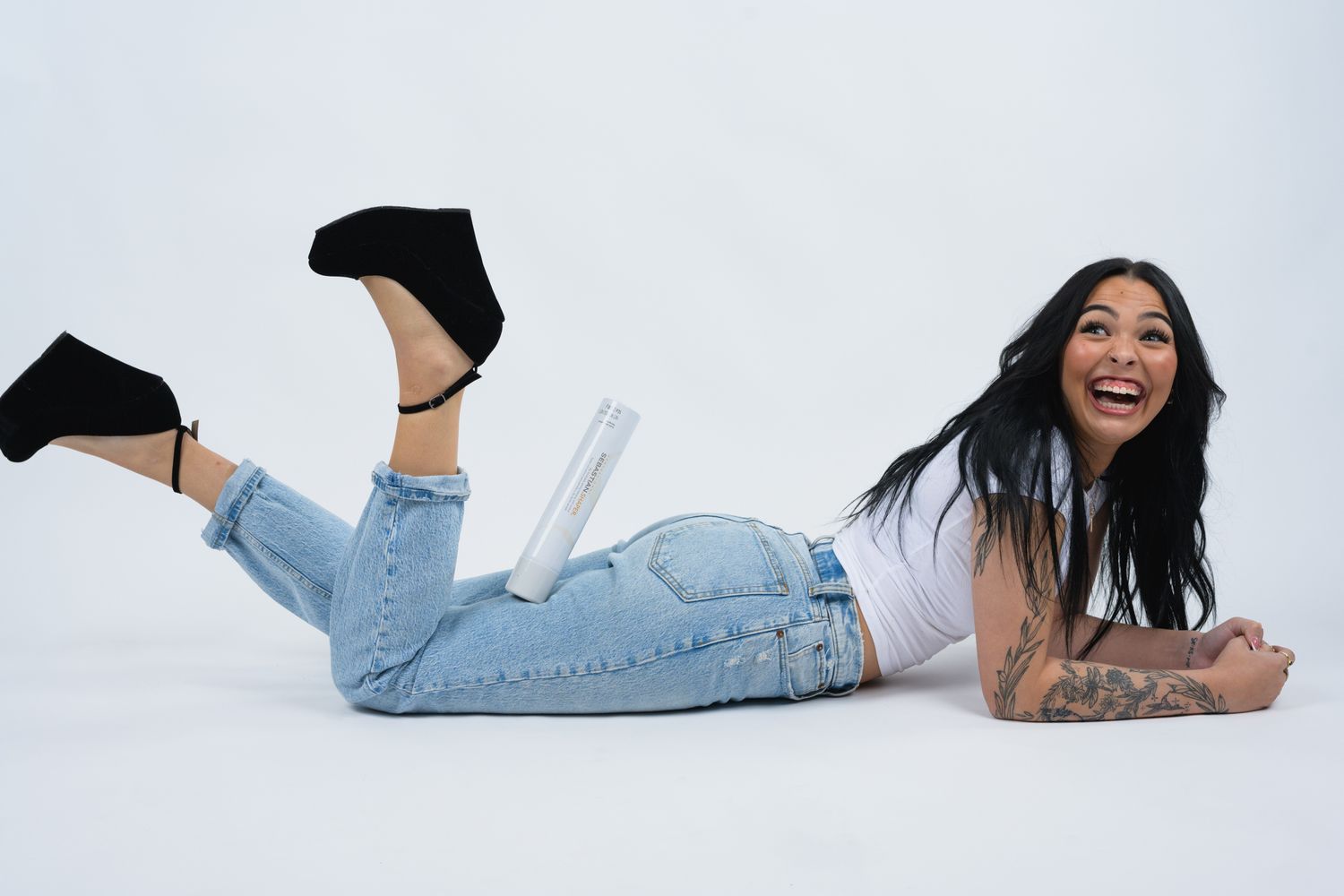 Casual lifestyle photo of person lying on white background wearing jeans and platform shoes.