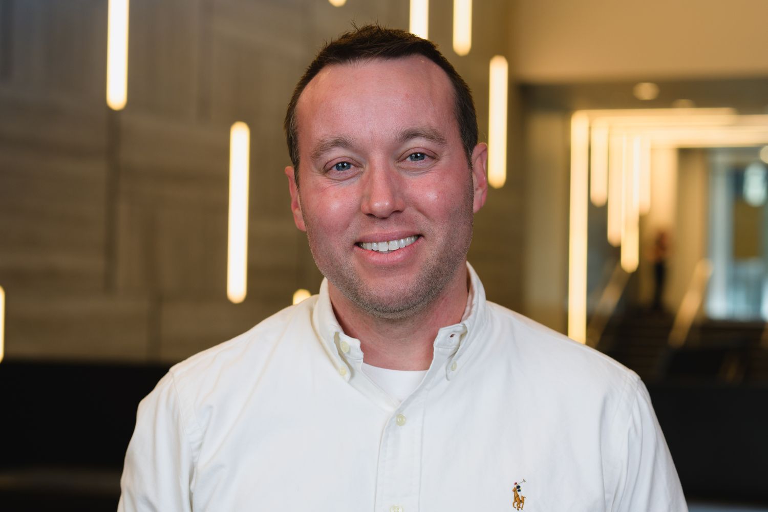 Professional headshot of person in white chef coat against modern office background.