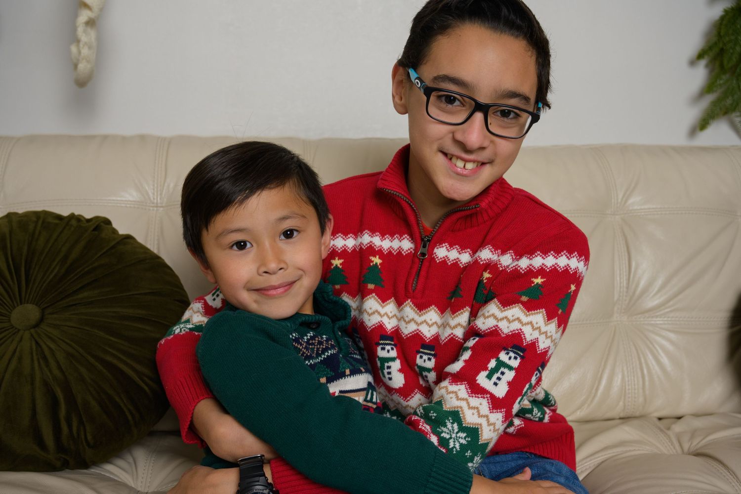 Two people in festive holiday sweaters sharing a warm embrace on couch.