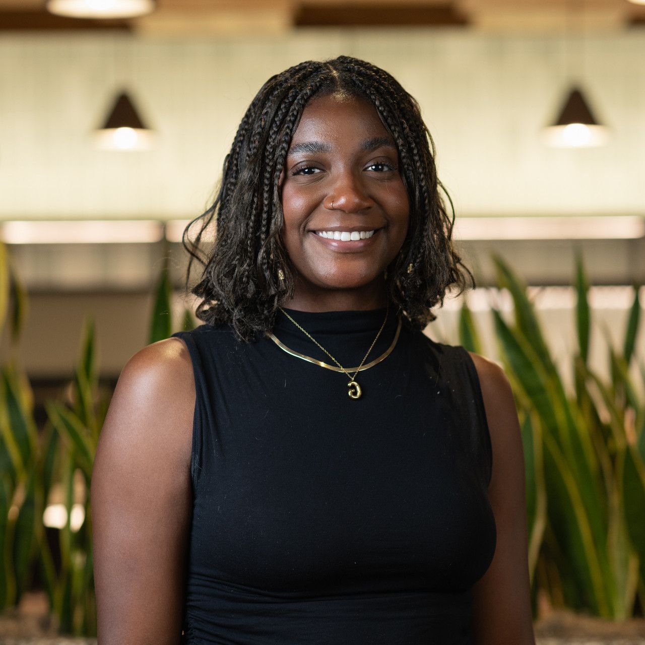 Professional portrait in black sleeveless top with indoor office background.