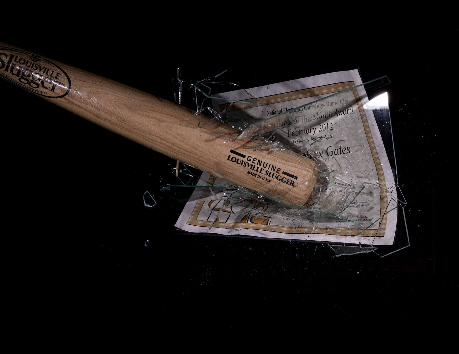 A wooden baseball bat shatters through a paper currency note against a black background.