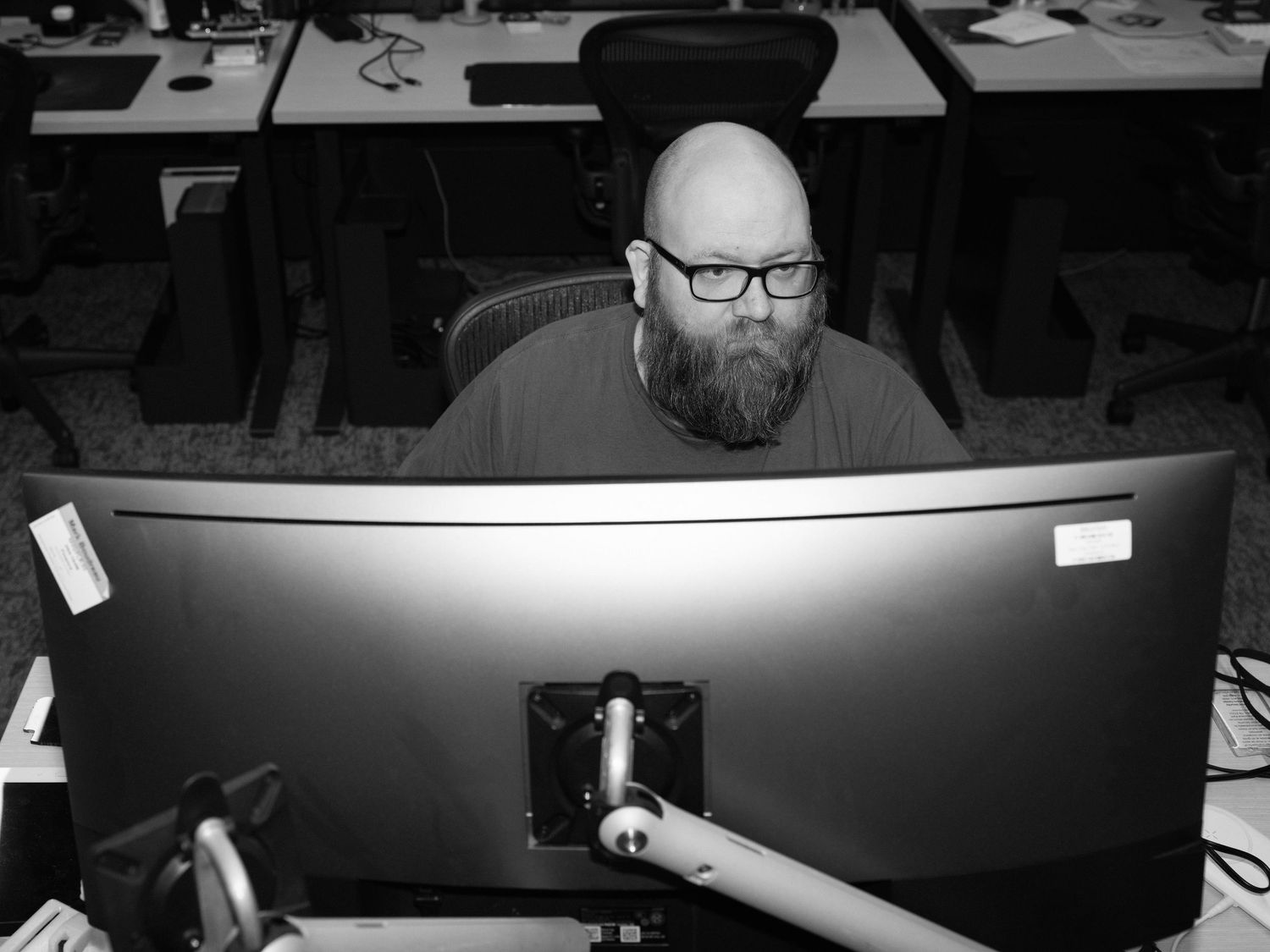 Dark office workspace with multiple computer monitors and desk setups.