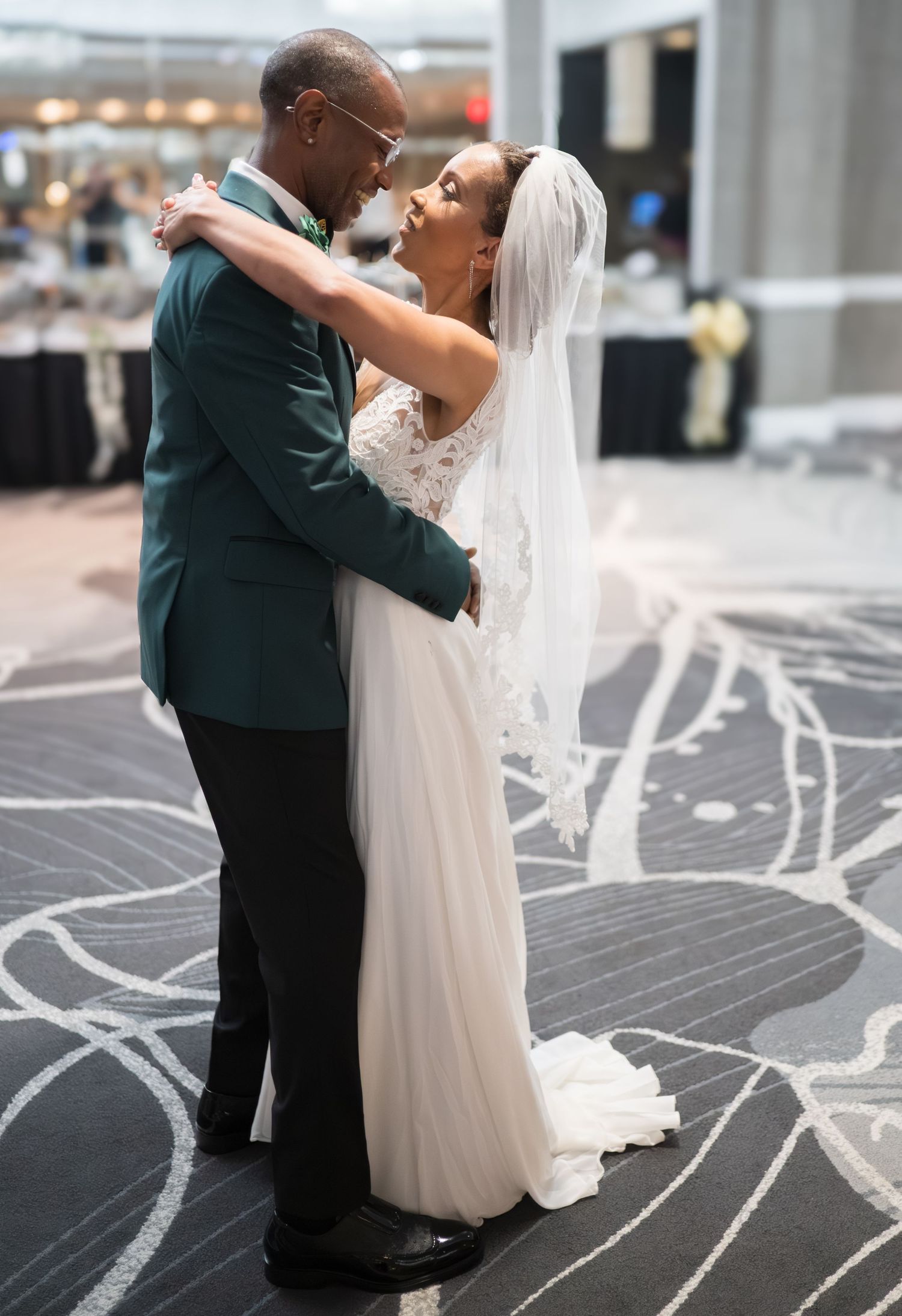 Wedding couple sharing their first dance on a patterned ballroom floor.