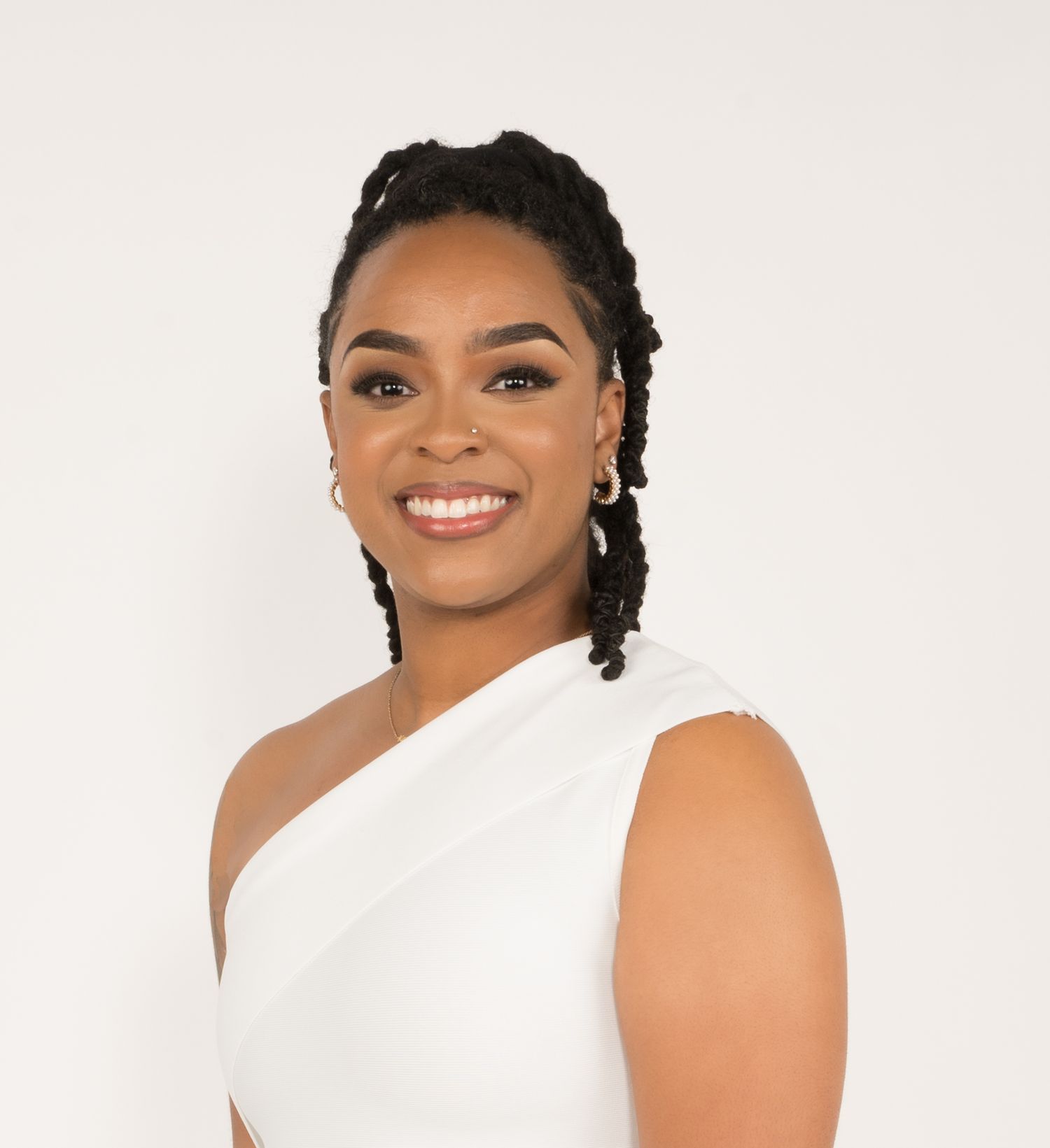 Professional portrait of someone wearing a white sleeveless top against a light background with a warm smile.