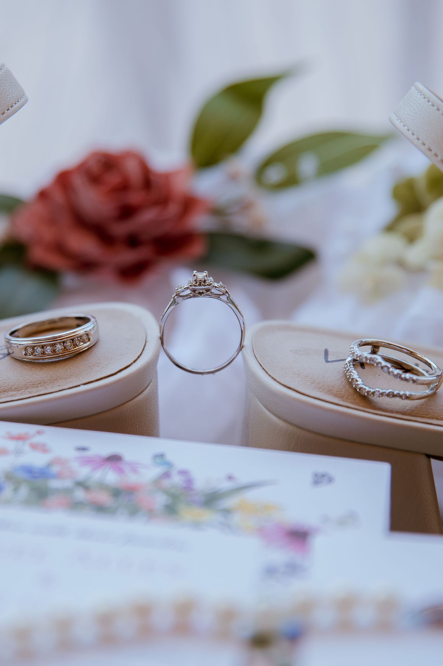 Close-up shots of elegant wedding rings and bands arranged on a floral patterned surface.