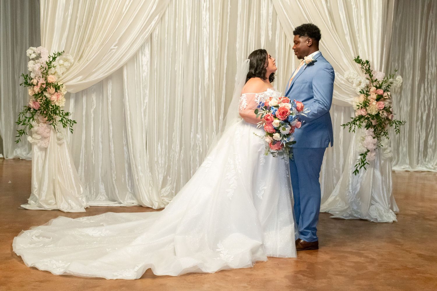 Indoor wedding photos with elegant white draping and floral arch decorations.