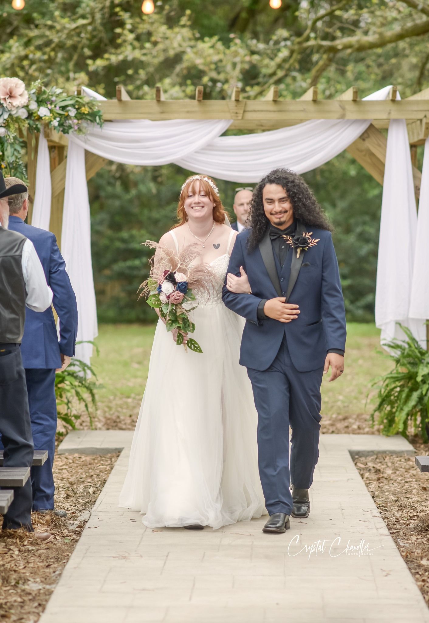 A joyful wedding celebration under white fabric draping and string lights in an outdoor garden setting.