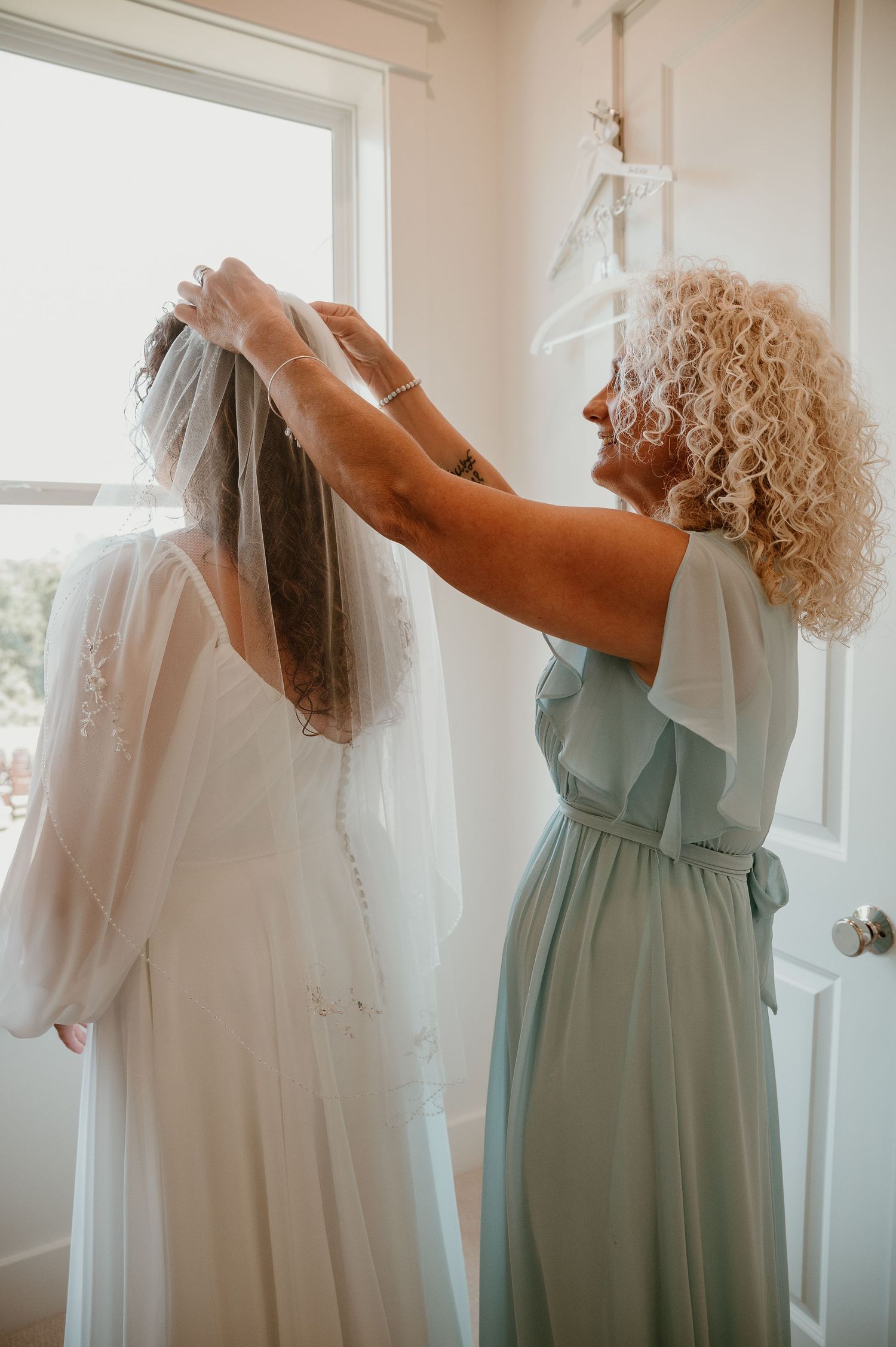 Mint green bridesmaid dress shown next to white wedding veil.