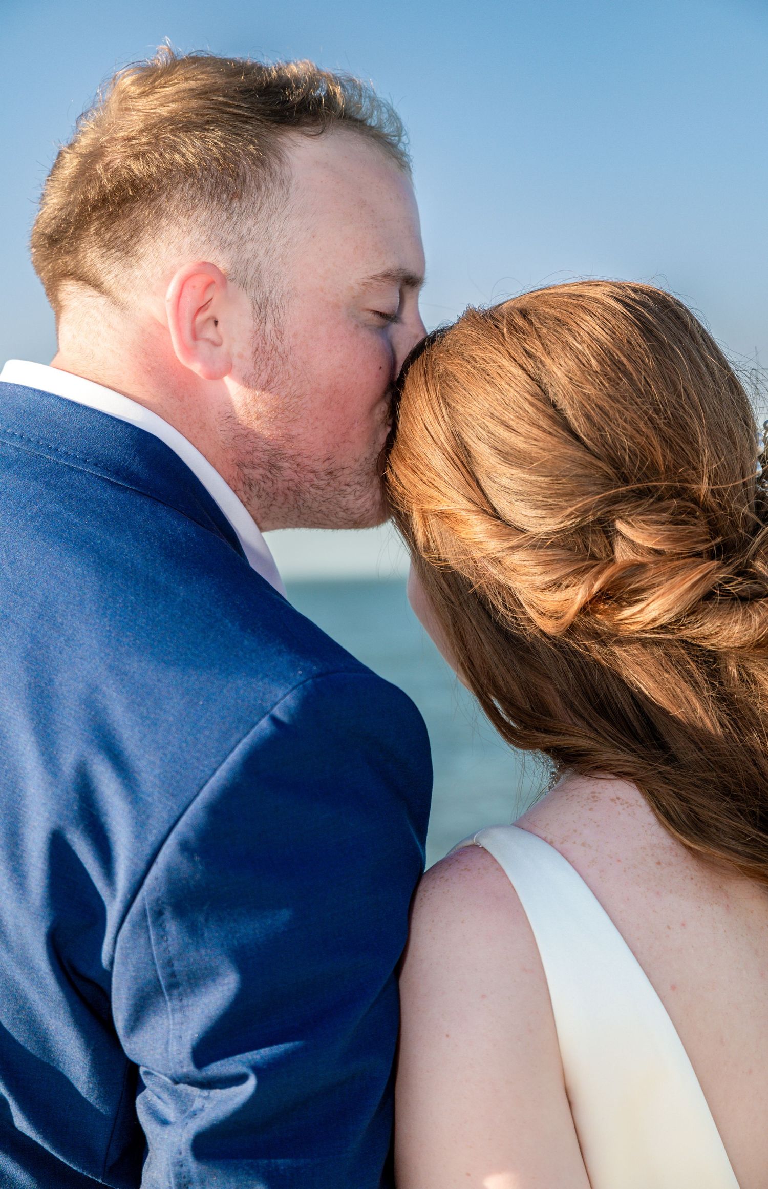 A series of romantic close-up shots showing a tender kiss against a blue sky background.