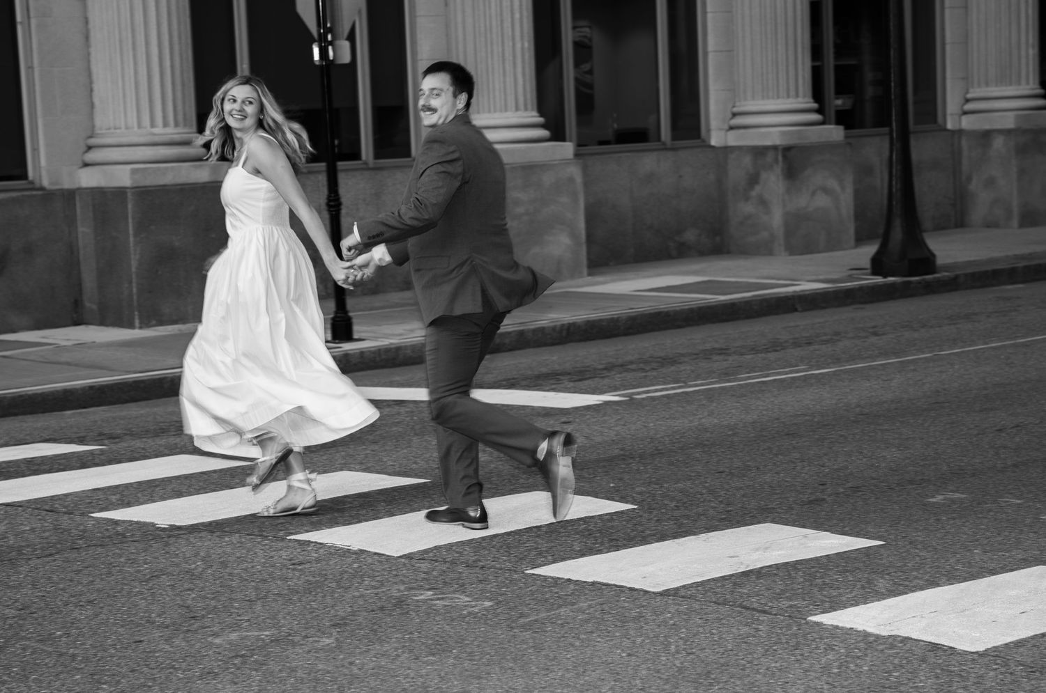 A sequence of black and white photos showing a couple walking across a crosswalk after their wedding ceremony.