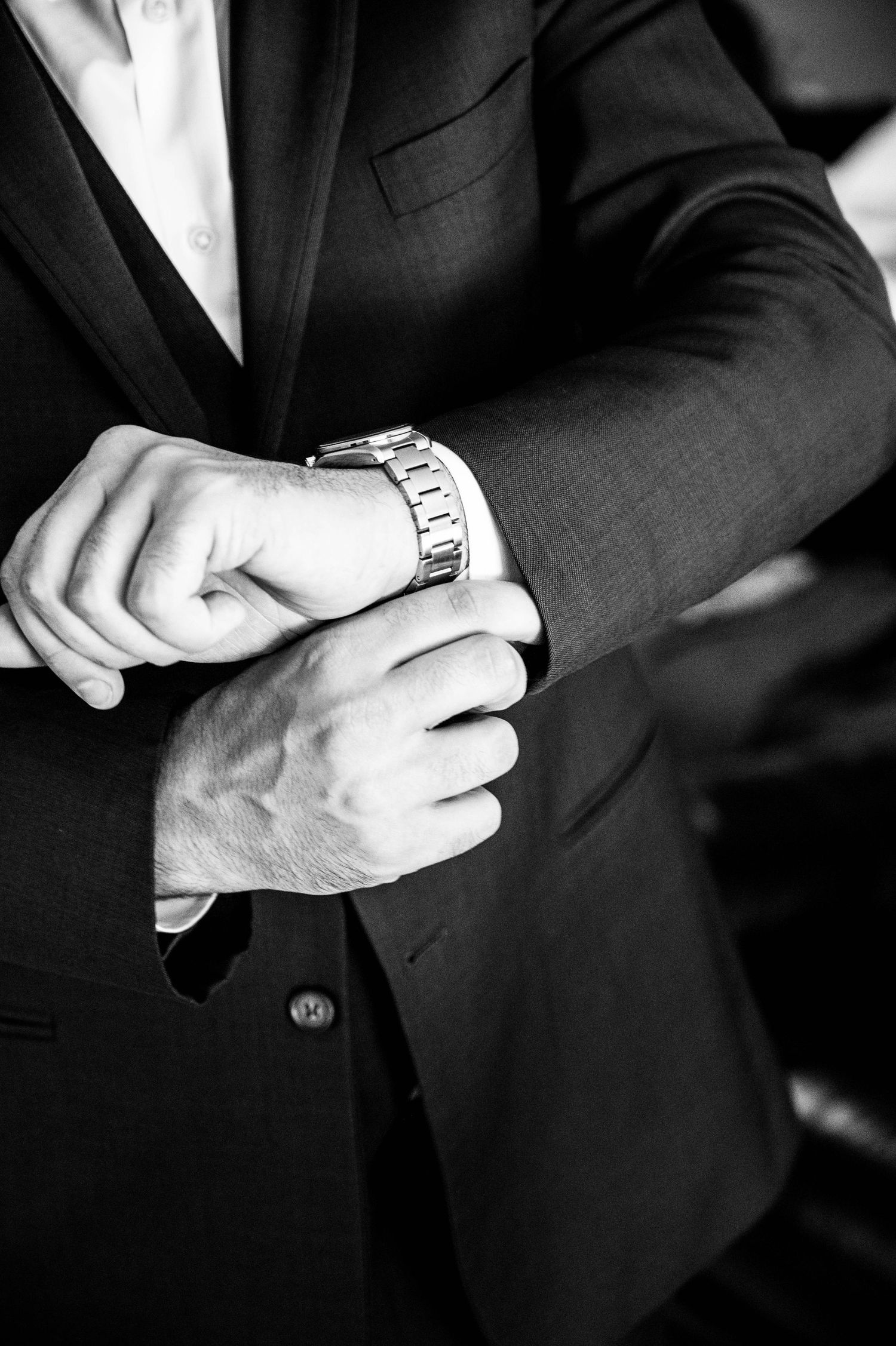 Close-up details of formal suit and watch in black and white.