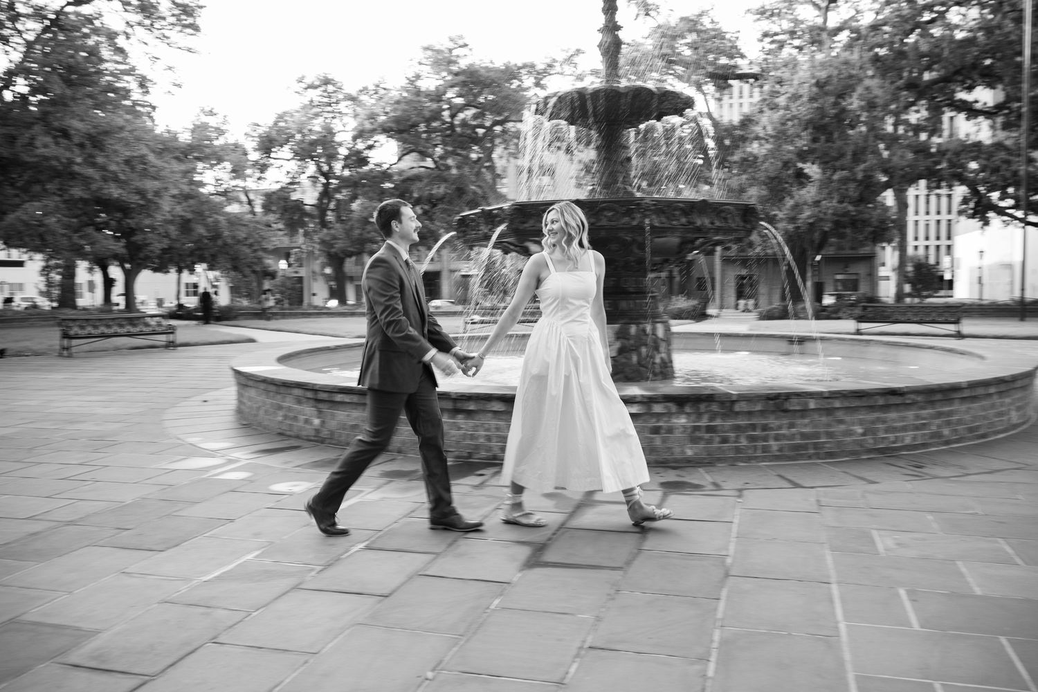 Wedding party walking along stone pathway in outdoor garden setting.