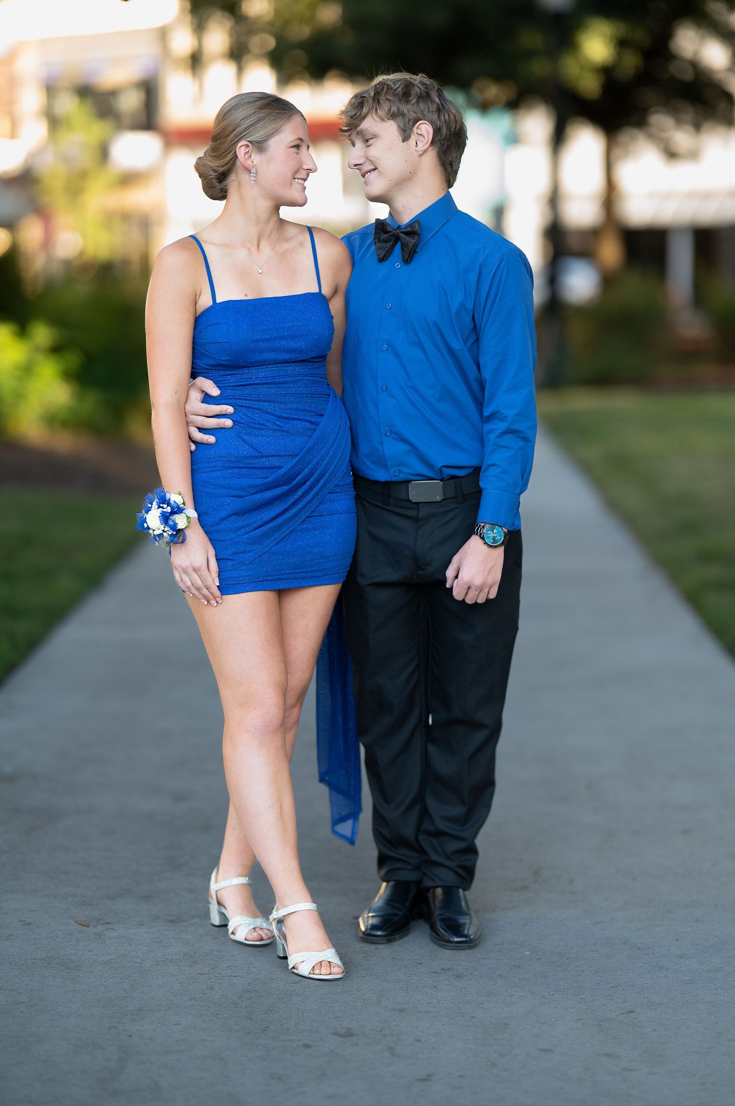 A couple in coordinating blue outfits walking together on a pathway at sunset.