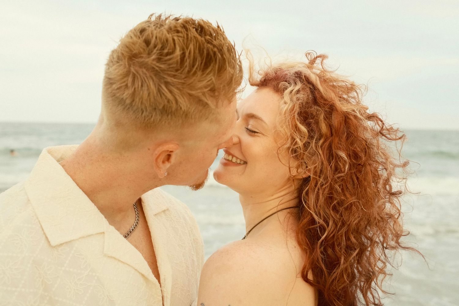 A romantic couple shares tender moments at the beach during sunset in a series of intimate photographs.