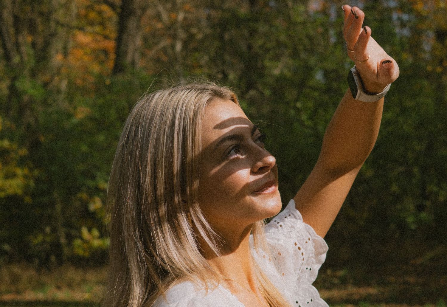 A person enjoying a sunny autumn day outdoors with shadows from tree branches creating patterns in the light.