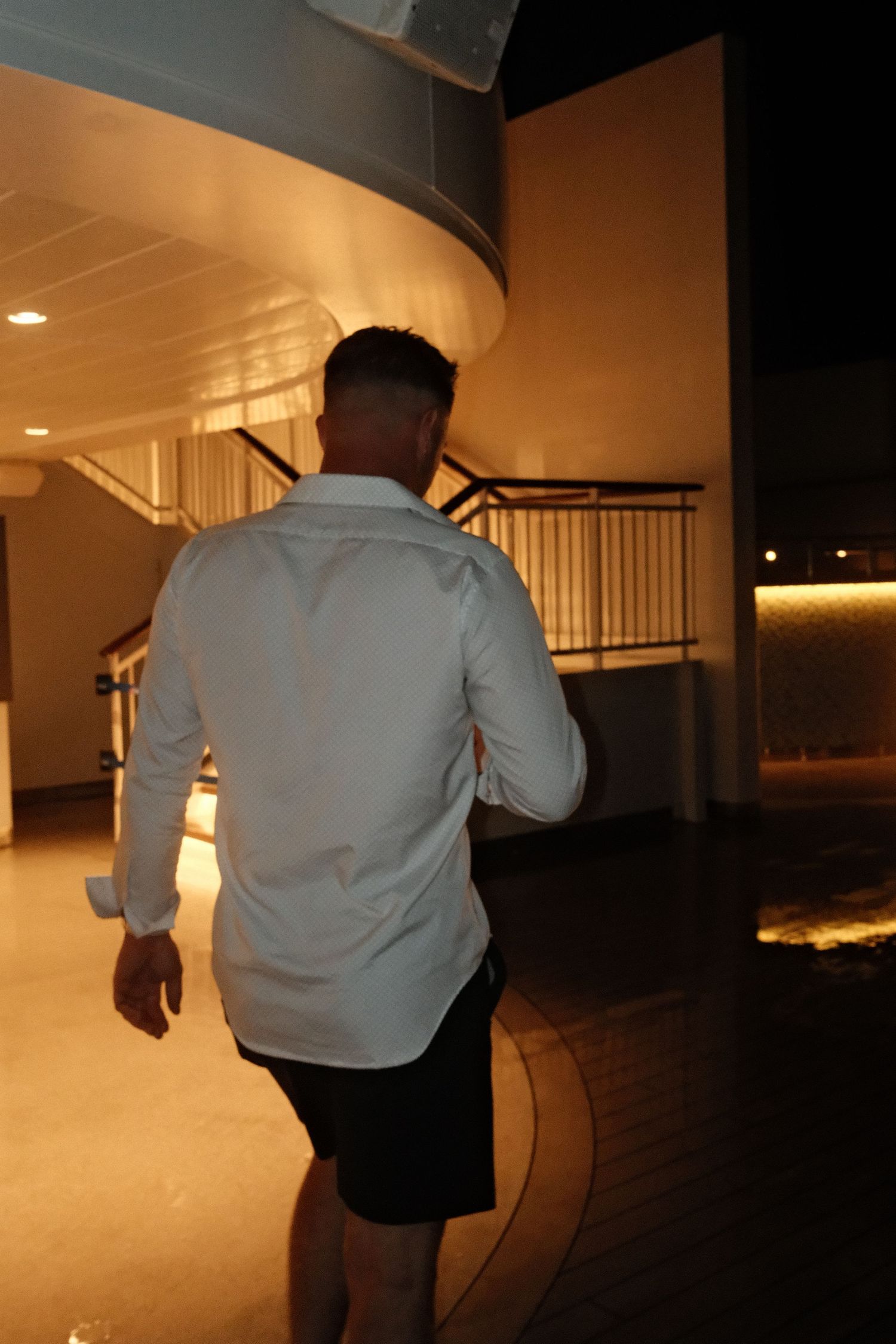 A sequence of silhouettes moving through a dimly lit indoor corridor with warm lighting.